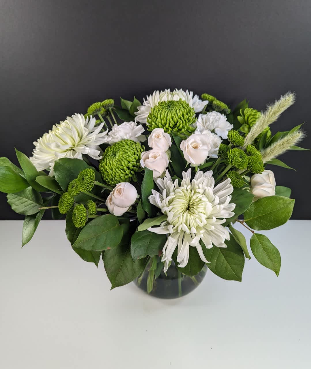 Meadow Mist Bouquet - Capture the Tranquil Beauty of Meadow Mist Floral Arrangement  Meadow Mist is a captivating arrangement of delicate white blooms and lush green foliage, evoking the tranquil beauty of a mist-covered meadow. This arrangement features:  -Green mums -White mums -White spray roses -White carnations  Immerse yourself in the serene ambiance of Meadow Mist, perfect for adding a touch of elegance and tranquility to any space.  