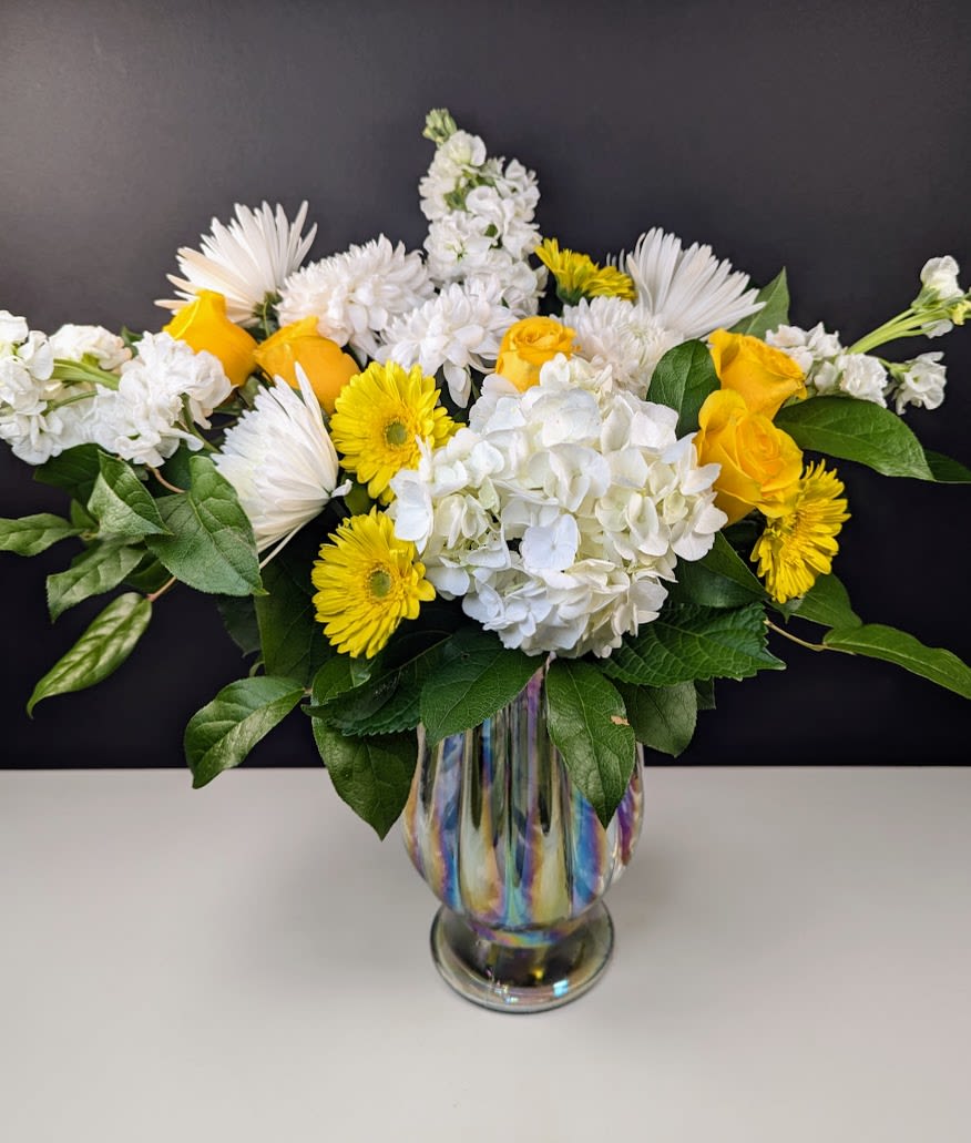 Gilded Petals Bouquet - Radiate Elegance with the Gilded Petals Bouquet  Brighten any space with the timeless beauty of the Gilded Petals Bouquet, a graceful blend of crisp whites and golden hues. This stunning arrangement features:  -White hydrangea -White mums -White stock -Yellow gerbera daisies -Yellow roses  Perfect for celebrations, gifts, or simply adding a touch of warmth and sophistication to any setting, this bouquet brings a luminous charm to every moment.