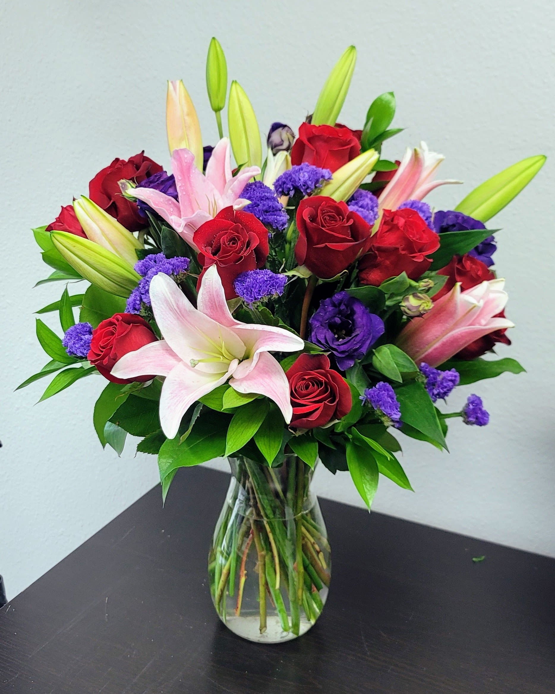 Truly Stunning Truly Stunning - Truly Stunning flower bouquet of spring flowers, including premium roses, lilies, and purple lisianthus. It's a captivating display presented in a simple, yet elegant glass vase. Approximately 16" H x 14" W.