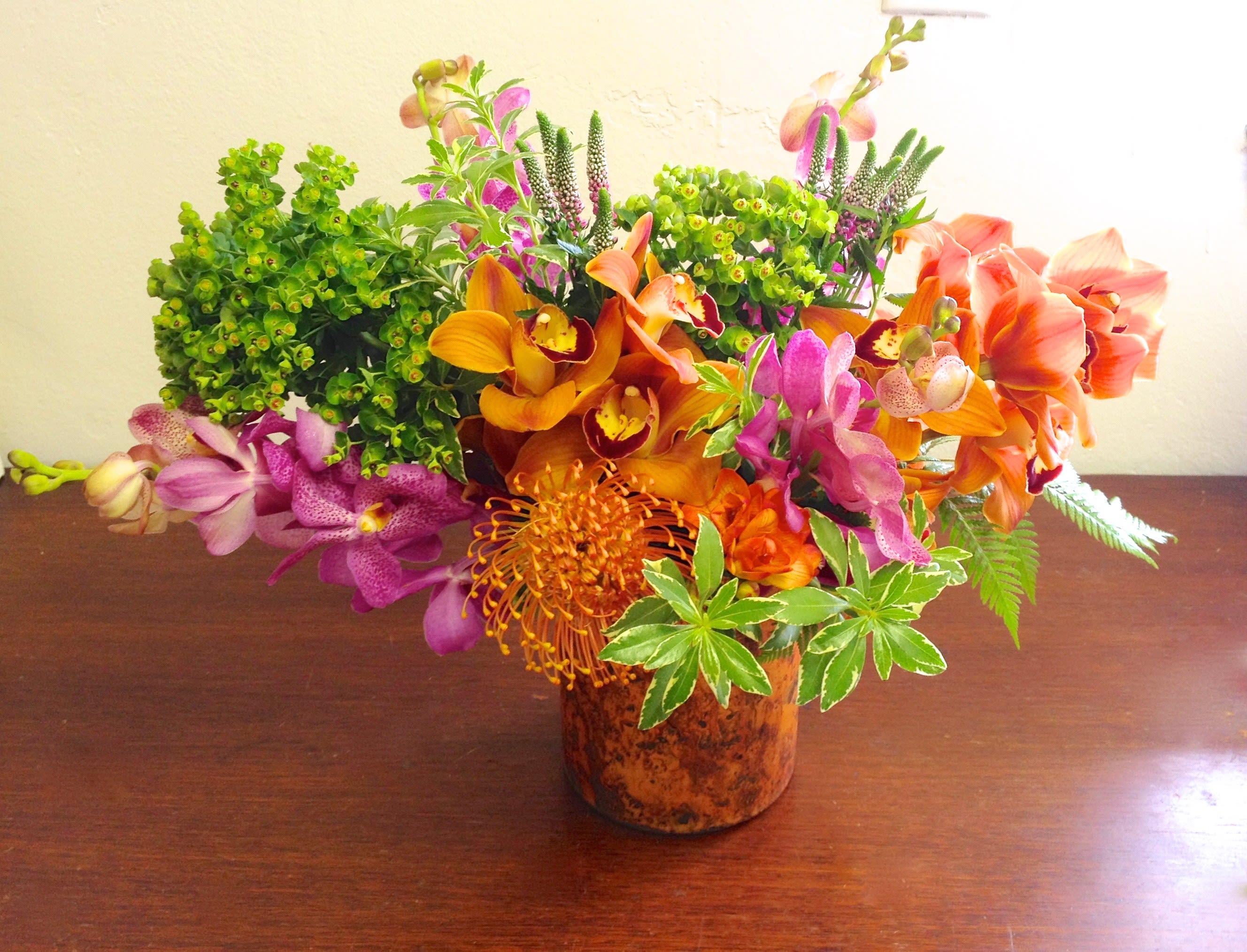 Take Me To Paradise - Escape to a tropical destination with this mix of exotic blooms.  Warm tones of orange, pink and purple orchids with protea come together to create this gorgeous symphony of tropical colors.   