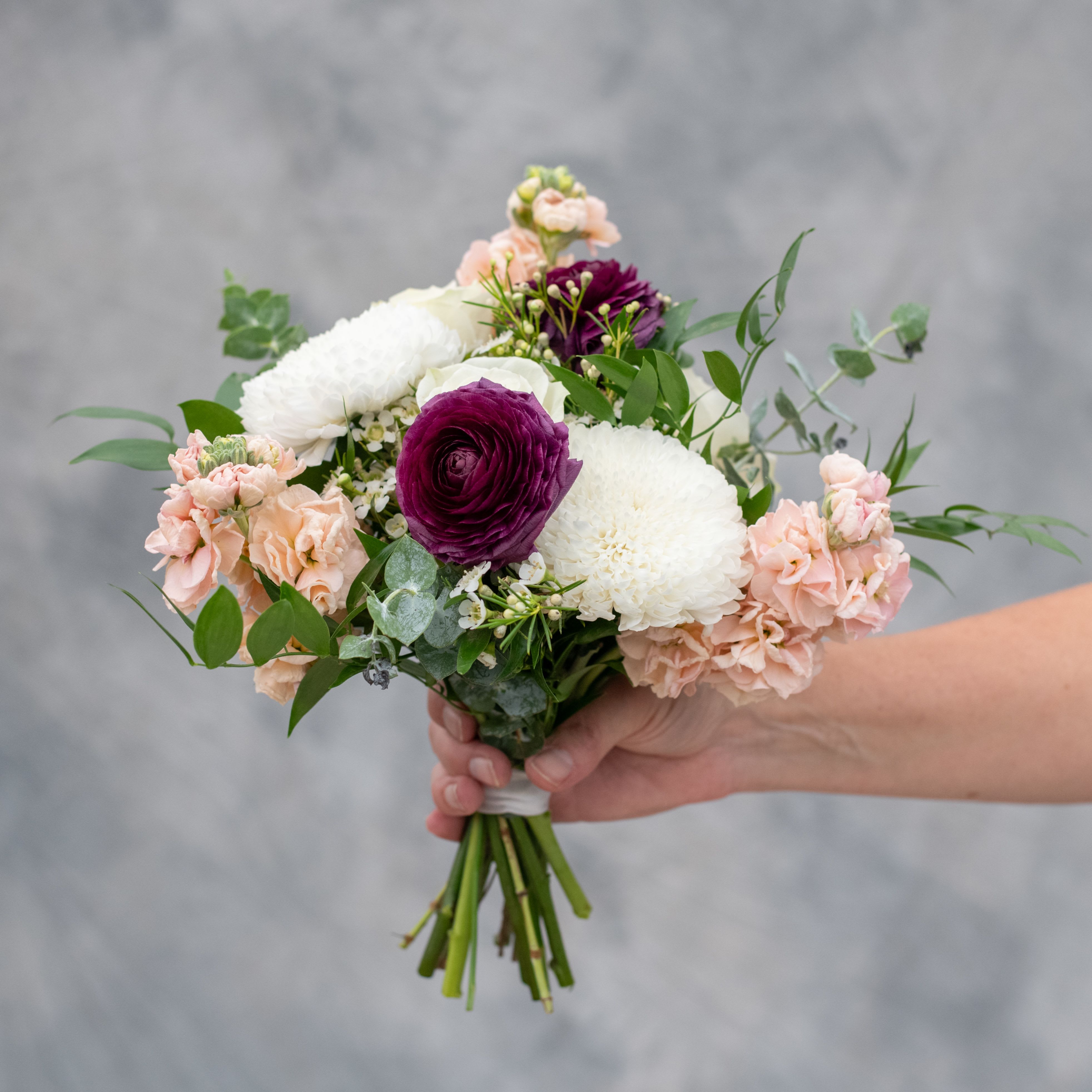  Premium Hand Held Prom Bouquet - Stand out in a crowd!  Once we are familiar with the color of the dress, we will choose a lovely selection of our most premium flowers and greenery to compliment your color scheme and finish it with coordinating ribbon.  The premium bouquet will contain flowers such as ranunculus, roses, stock and more. We suggest calling or stopping in to order this custom item. 