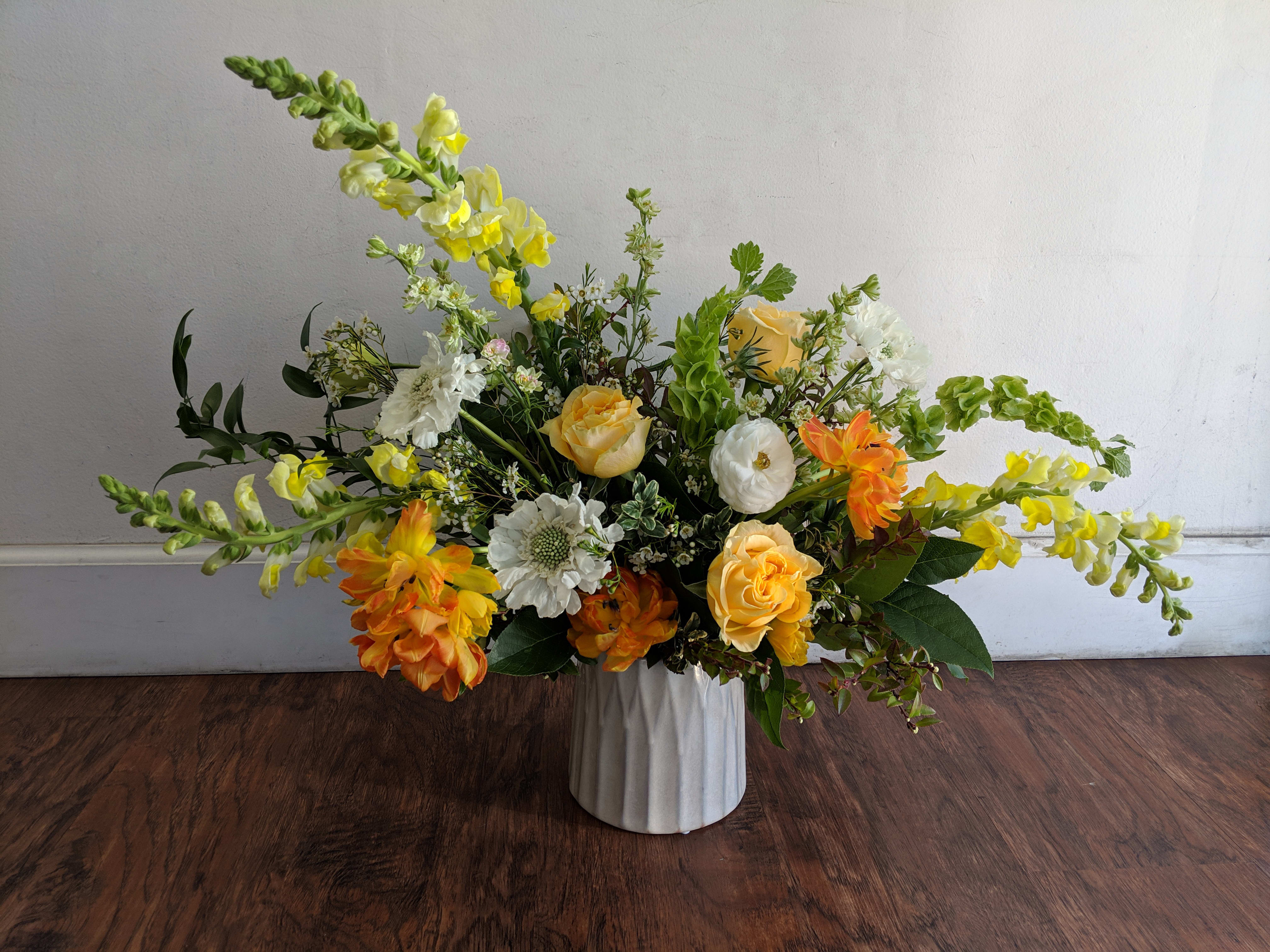 Springing Blooms - This warm toned arrangement pops with yellows and oranges- bringing spring into any space. 