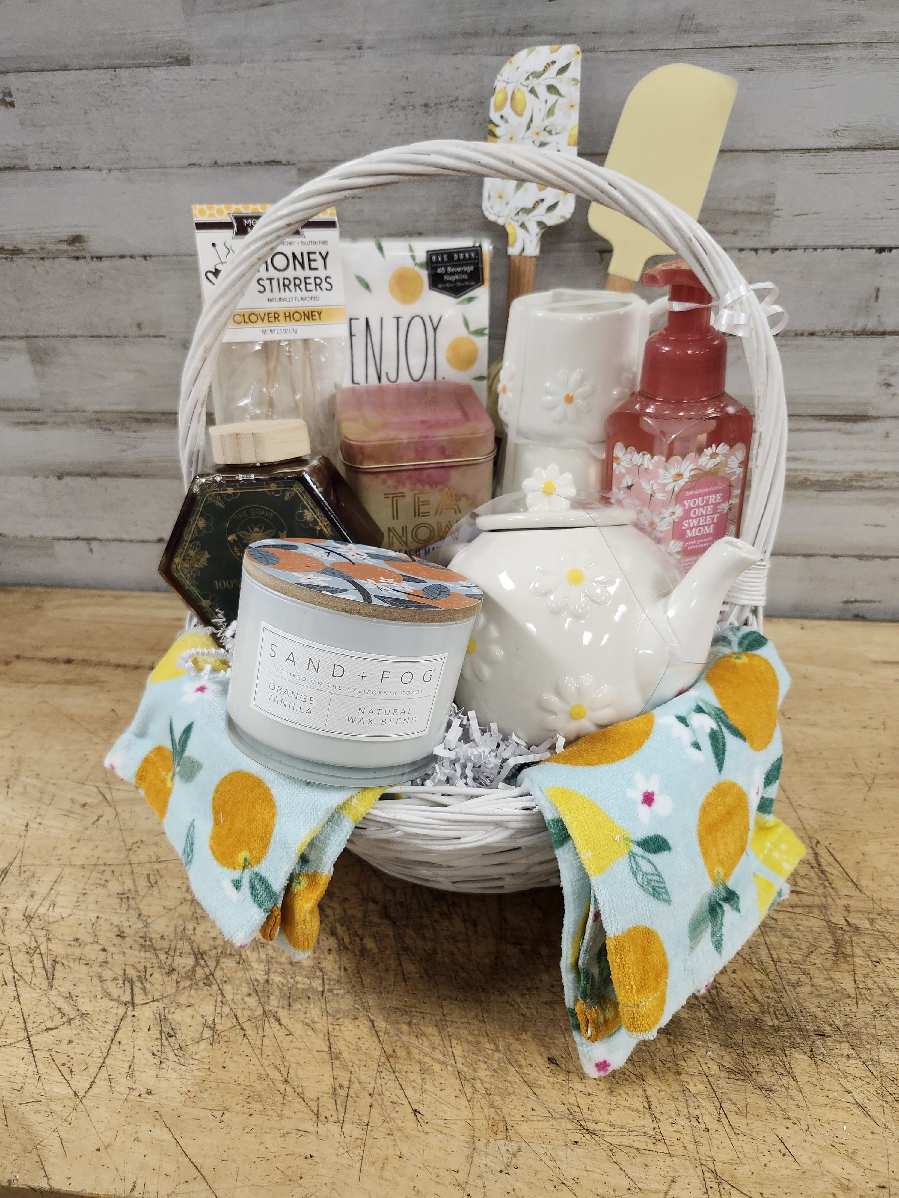 Sweet Tea Time - $195 - For practical use or cute display this tea set gift basket is sure to please!  Featuring: - Ceramic Tea Pot - Matching Mug Set - Tea Towels - Decorative Napkins - Spatula Set  - Mango Tea - Local Honey - Honey Stir Sticks - Candle  - Hand Soap