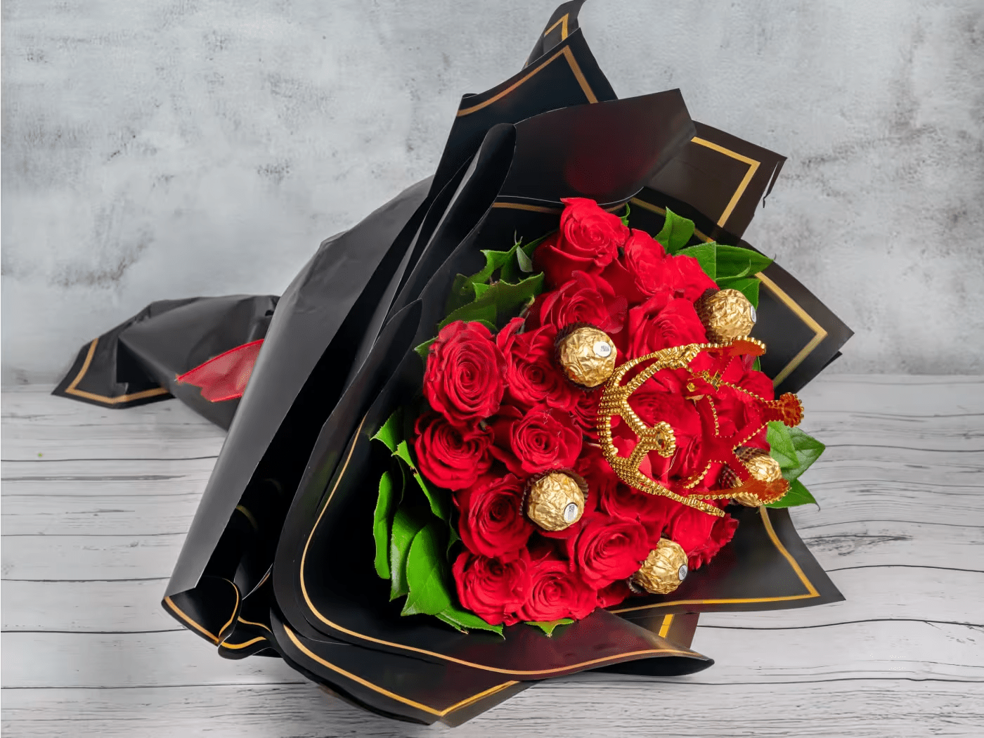 Royal Indulgence - A luxurious arrangement of 24 bold red roses, accented with rich green foliage and adorned with indulgent gold-wrapped chocolates. Elegantly wrapped in sleek black paper with gold trim, this bouquet makes a statement of opulence and grandeur. Perfect for romantic gestures, special celebrations, or when you want to show appreciation in the most decadent way. Make any moment unforgettable with this exquisite gift.