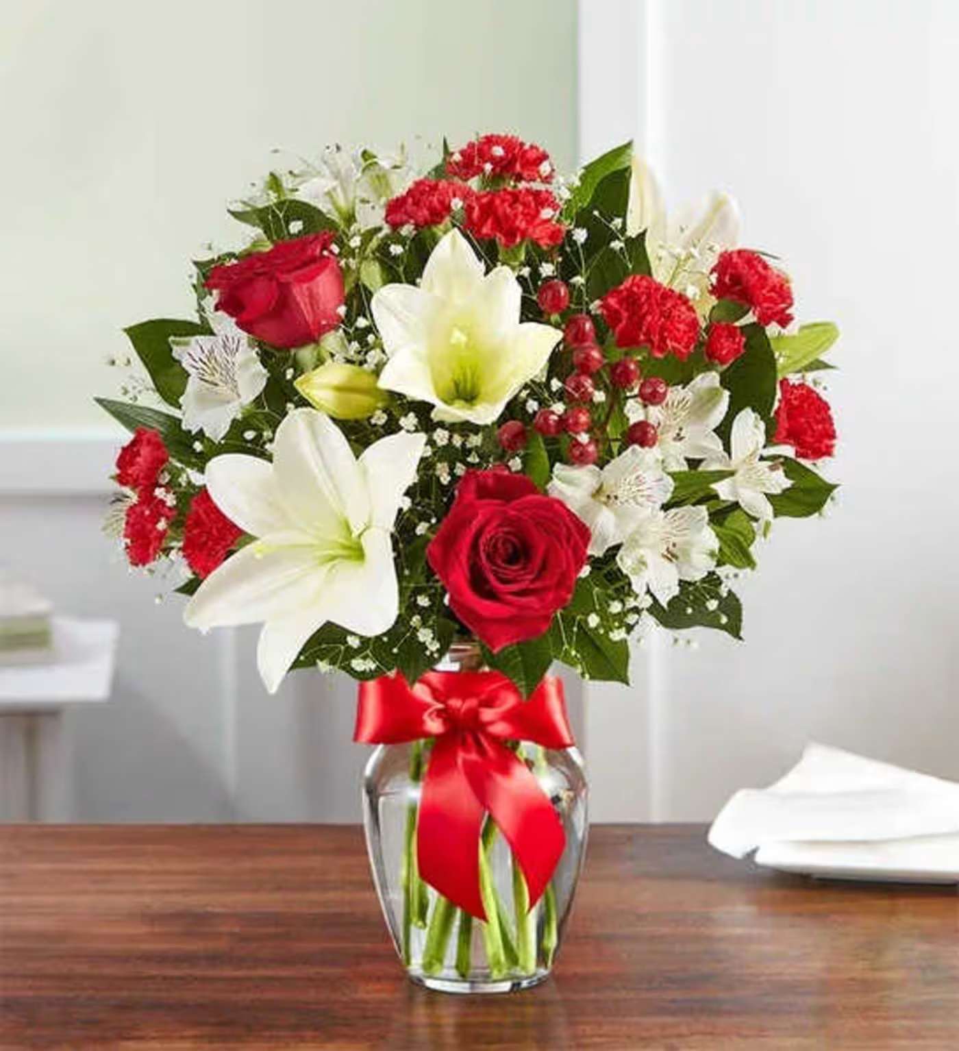 Fields of Europe® Christmas - The rustic beauty of the European countryside is beautifully captured in our best-selling holiday bouquet. Fresh-picked red &amp; white blooms are hand-arranged in a glass vase tied with red ribbon, delivering your warmest wishes, while bringing you closer to the people you love.  All-around arrangement with red roses and mini carnations; white Asiatic lilies and Peruvian lilies (alstroemeria); accented with baby’s breath, hypericum berries and assorted Christmas greenery Artistically designed in a clear glass vase tied with satin red ribbon; vase measures 8&quot;H Premium arrangement measures approximately 19&quot;H x 15&quot;W Deluxe arrangement measures approximately 18&quot;H x 14&quot;W Standard arrangement measures approximately 17&quot;H x 13&quot;W Our florists hand-design each arrangement, so colors, varieties and container may vary due to local availability To ensure lasting beauty, Asiatic lilies and Peruvian lilies may arrive in bud form and will fully bloom over the next few days