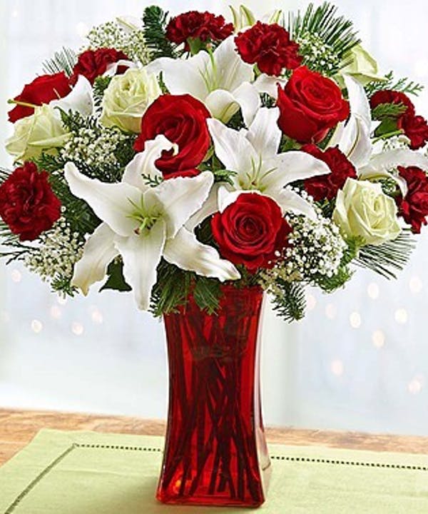 The magic of love The magic of love - Our enchanting bouquet of red roses, white lilies, alstroemeria and evergreens delivers all the magic of the holidays right to their door—no sleigh required! Designed in a red gathering vase, this spellbinding arrangement will leave all of the special people in your life feeling merry and bright.