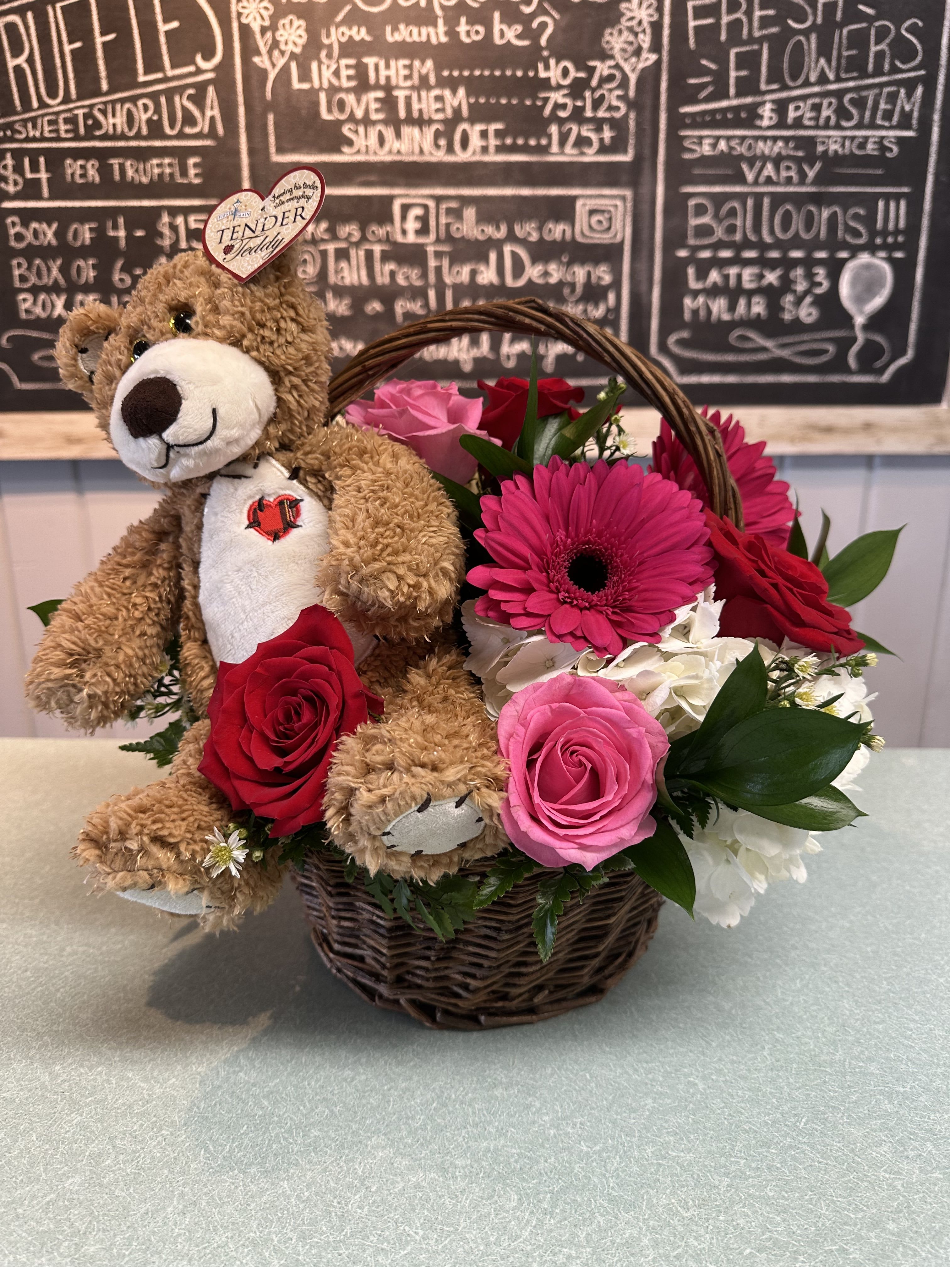 Love Me Tender Love Me Tender - White premium hydrangea, pink sweet unique roses, red freedom roses, hot pink gerbera daisy and assorted greenery in a brown wicker basket with TENDER TEDDY bear.