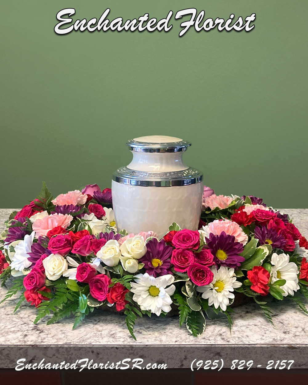 Loving Legacy - Urn Wreath - A heartfelt urn wreath that honors cherished memories with grace, showcasing a vibrant palette of red, purple, pink, and white. Featuring chrysanthemums, roses, carnations, spray roses, and poms, this tribute is accented with verdant leather fern, and pittosporum for a touch of elegance.  Urn wreaths are traditionally ordered by immediate family members, and are sent to reception sites before the ceremony begins. Intended to be set on a flat surface, with an urn or framed photo placed within the wreath center, creating a loving tribute and providing solace and comfort during times of loss.  Please Note: Urn wreath does not include urn.  Approximate Dimensions: 6&quot; Wreath Height 28&quot; Wreath Diameter
