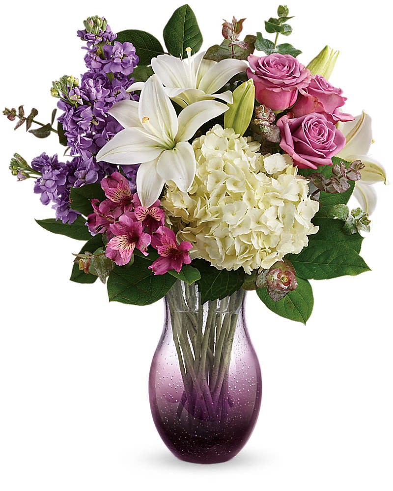 Teleflora's True Treasure Bouquet - Celebrate mom for the true treasure she is with this incredible keepsake filled with a luxurious lily bouquet. Hand-blown in bubble glass the one-of-a-kind ombre vase will be a dÃ©cor favorite for years to come! White asiatic lilies white hydrangea lavender stock and purple alstroemeria are accented with spiral eucalyptus and lemon leaf. Delivered in an All Eyes On You vase.