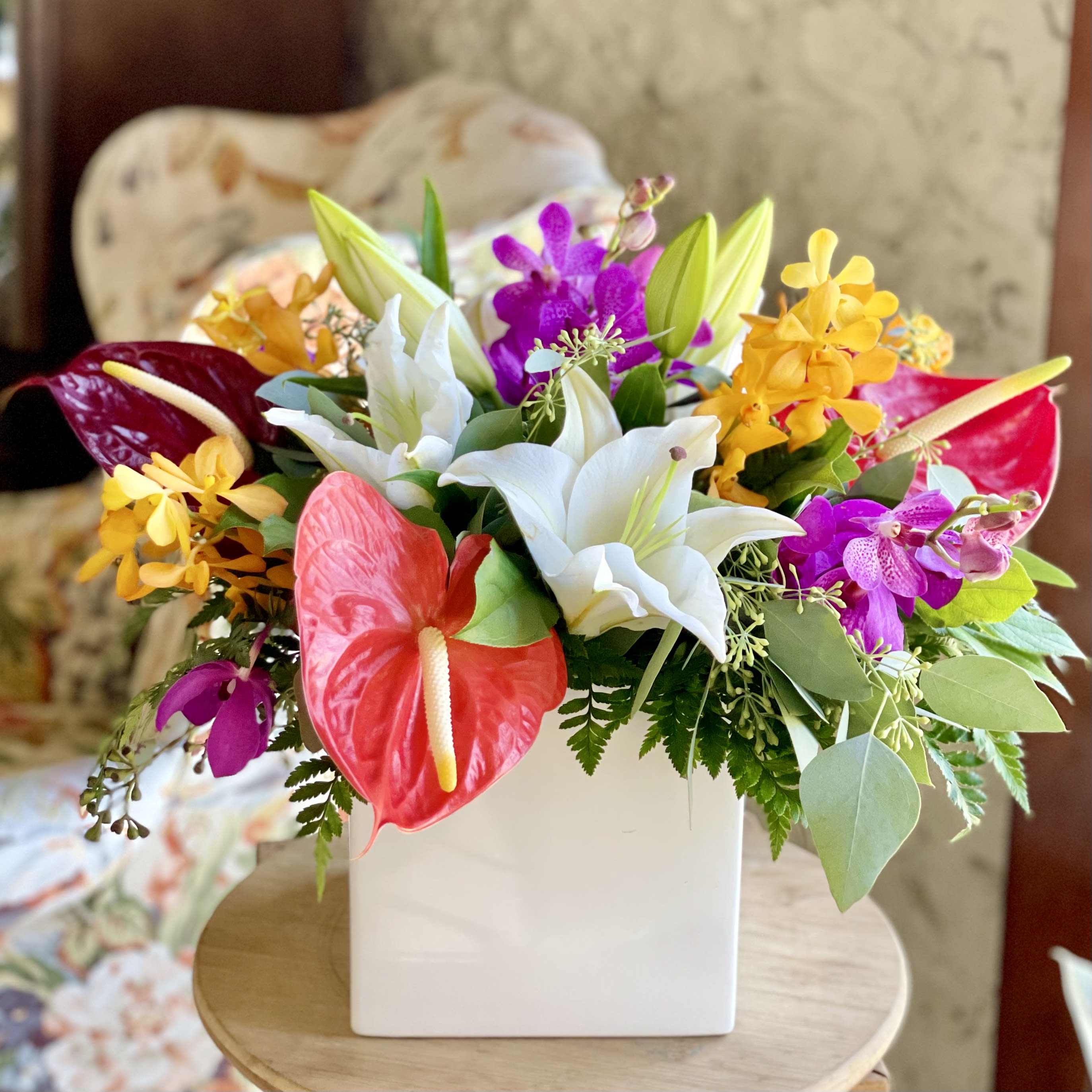 Island Dreams (SF401) - This stunning arrangement features beautiful tropical flowers like anthuriums, mokara orchids, and Casablanca lilies in a ceramic white cube vase. The vivid colors, unique textures, and sweet fragrances of this arrangement transports you to a lush, sun-kissed island retreat! 