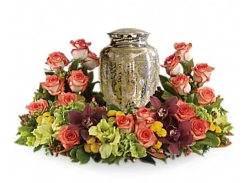 Sunset Wreath Sunset Wreath - A rich and subtly hued garden expresses sympathy most thoughtfully, in a gentle oval arrangement that honors and embraces a cherished memory. Orange roses blend with other beautiful flowers such as stems of cymbidium orchids, gladioli, chrysanthemums, hypericum and other delicate greens.Please note: Arrangement does not include urn.