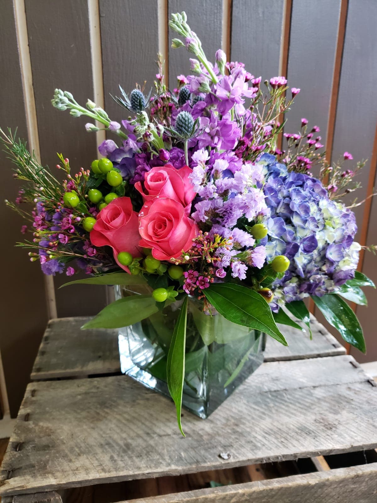 Bloom by Kokee - a mixes flowers vase arrangement  such a , purple hydrangeas from Holland, Russian cut roses from Ecuador,  purple statics, pink wax on a cuculus green leaf nest.