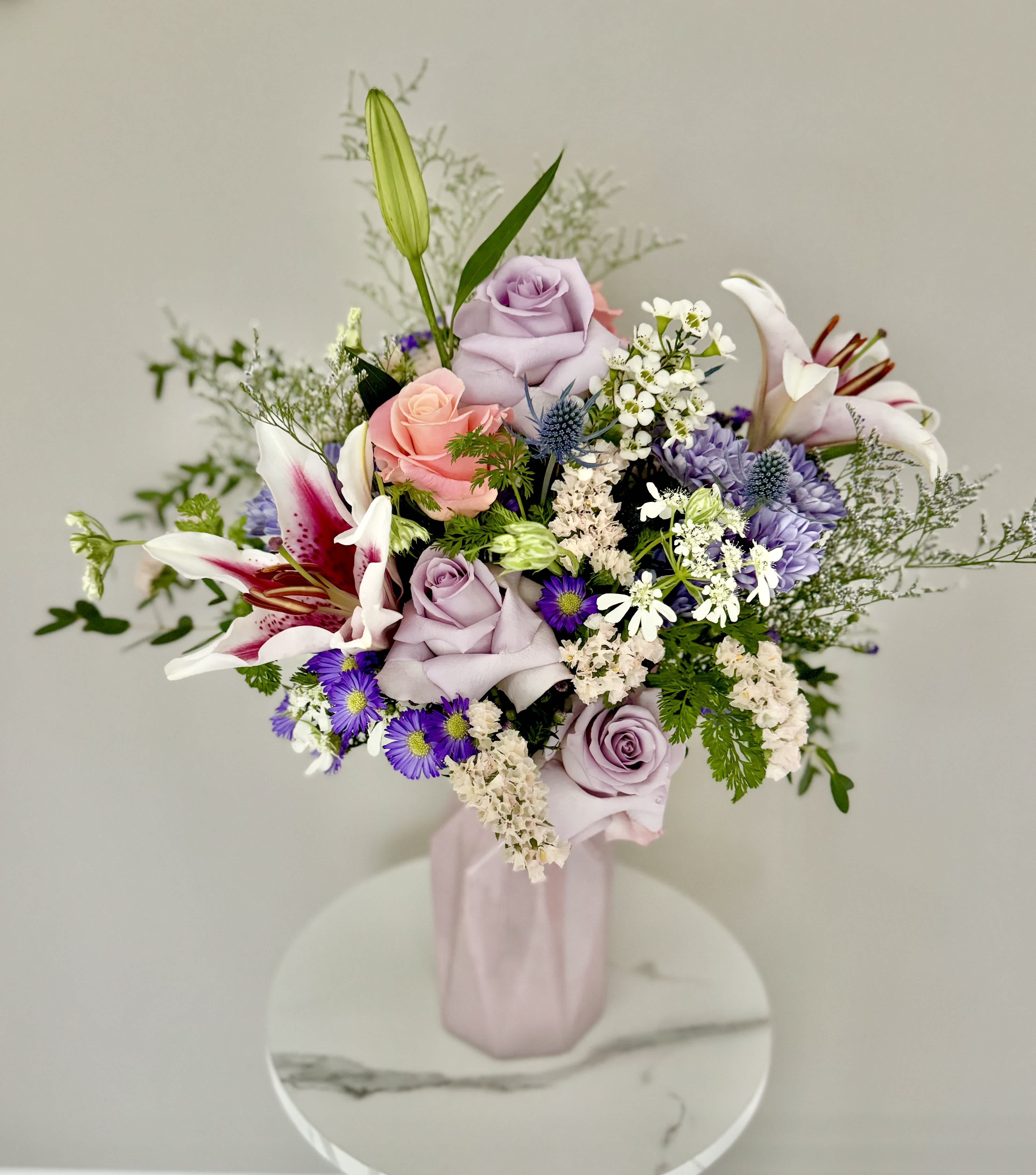 That Spring Feeling - Feel the lovely days of Spring with these beautiful arrangement featuring flowers with spring colors of pinks and pastels that are specially selected by the Florist, along with the delicious scent of Lilies. It will bring so much color, light and fragrance to any space.  Arrangement will be in a vase in pastel colors.