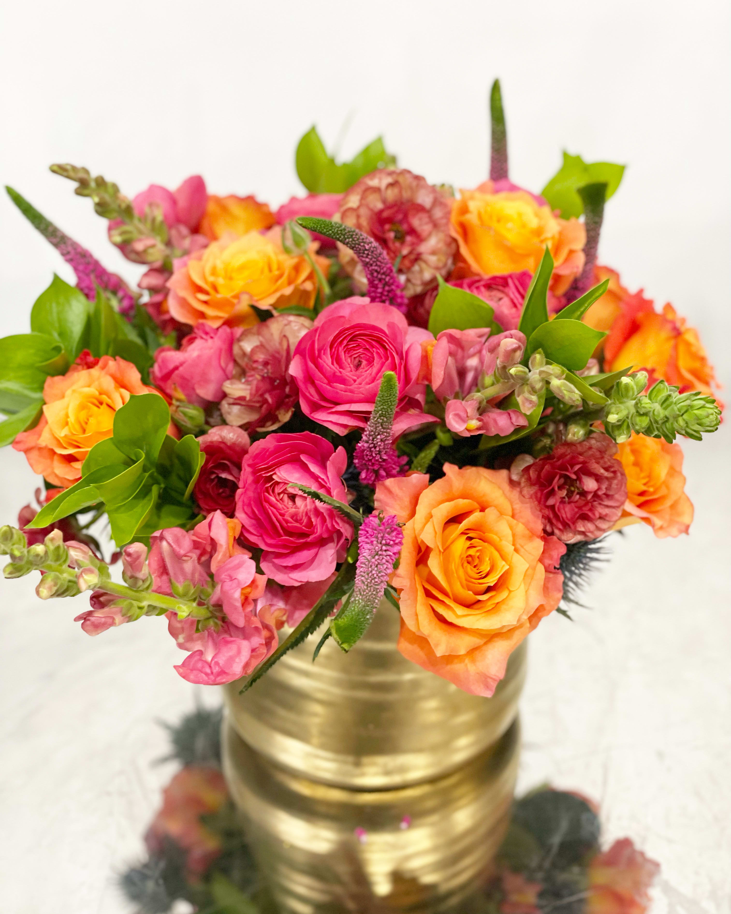 Siesta  - This low and lush brightly colored arrangement is the best way to send some happiness to a colleague or loved one. Perfect for a dining table or coffee table. This will be the very best the market has to offer in hot colors. We will choose the flowers, you choose the size. This picture is representation of the color palette. While a lot of the flowers will be sourced, some may need to be exchanged with comparable or higher quality flowers.    NOTES: We will choose the freshest and most interesting ingredients at the market to make this arrangement shine. Vessel may be substituted depending on availability. ]   