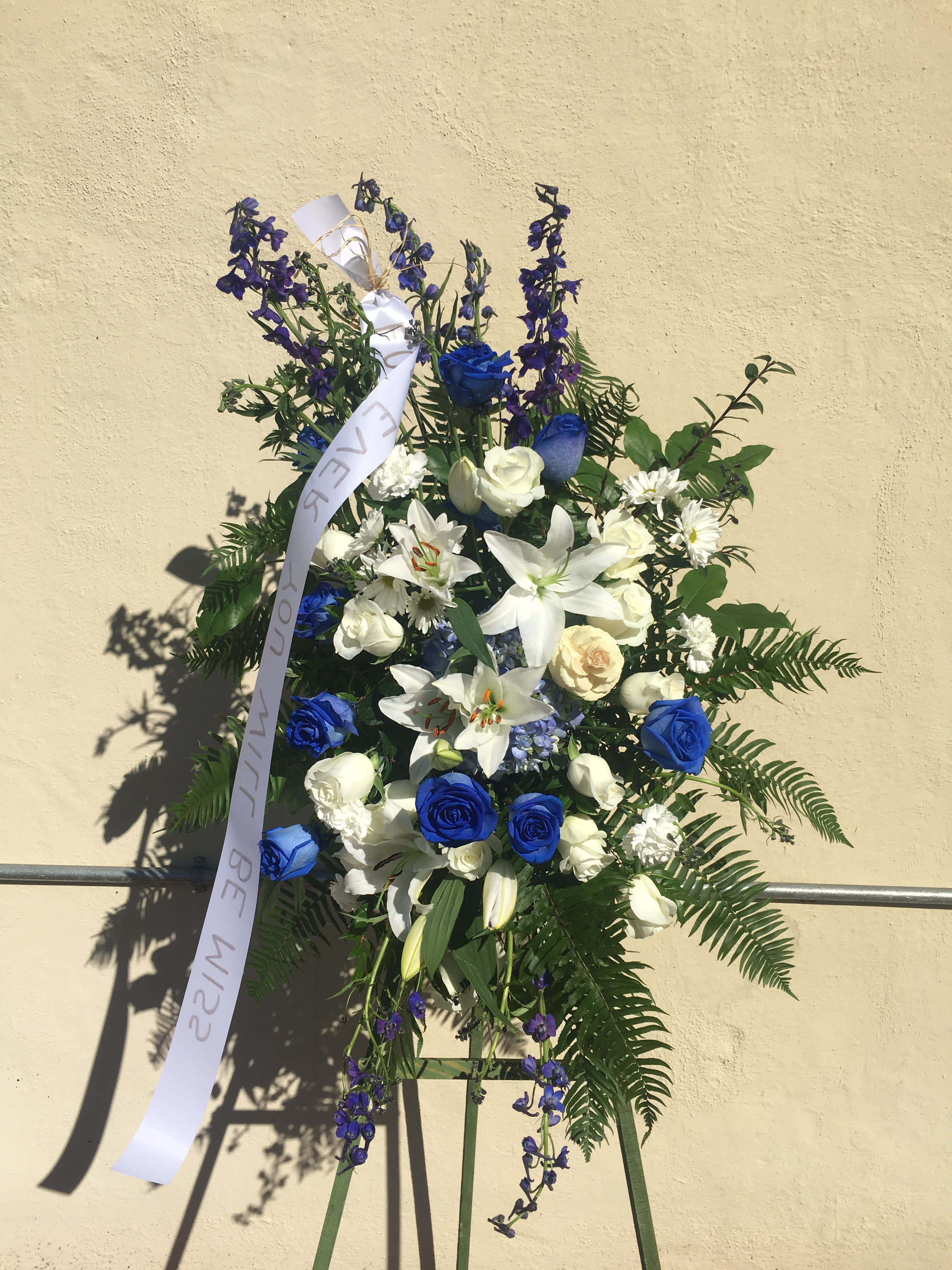 Sea of Love Spray Sea of Love Spray - Glamorous blue roses and blue Belladonnas artistically arranged with white lilies and roses and other whites and greens like sword ferns.