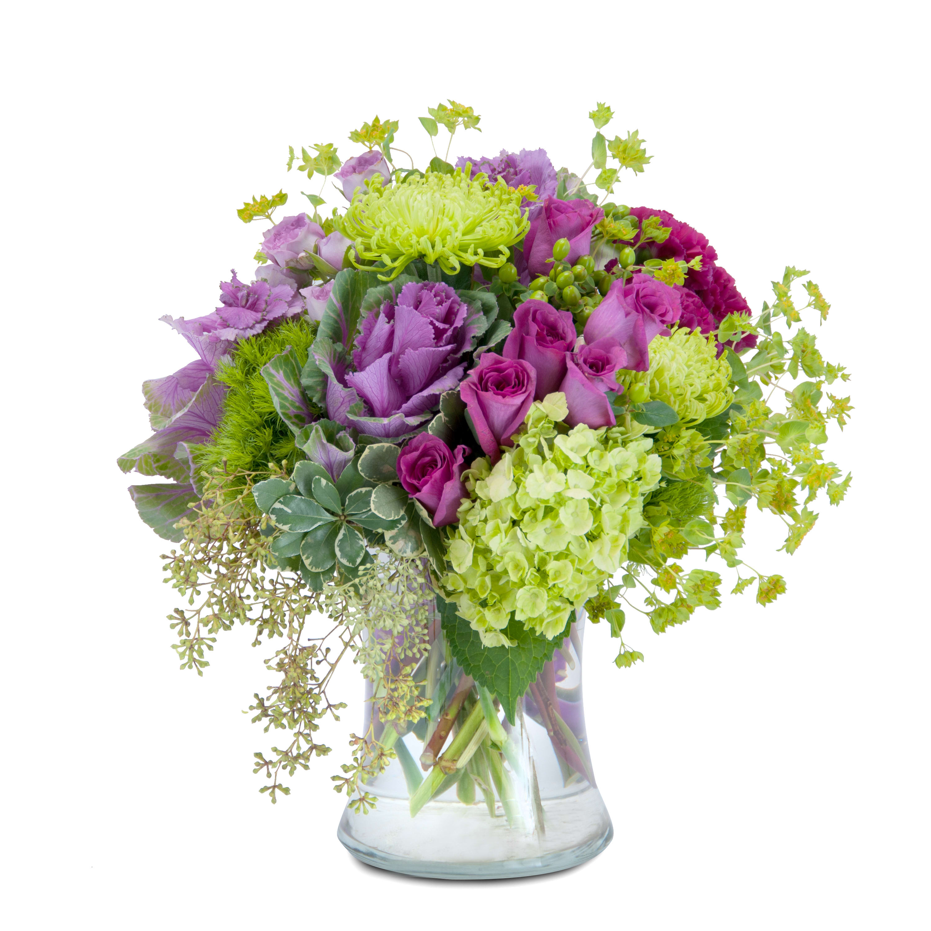 Magenta Mystery Magenta Mystery - A magical mixture of magenta and green flowers, including roses, hydrangea, hypericum berry and ornamental kale, designed in a large clear glass vase.