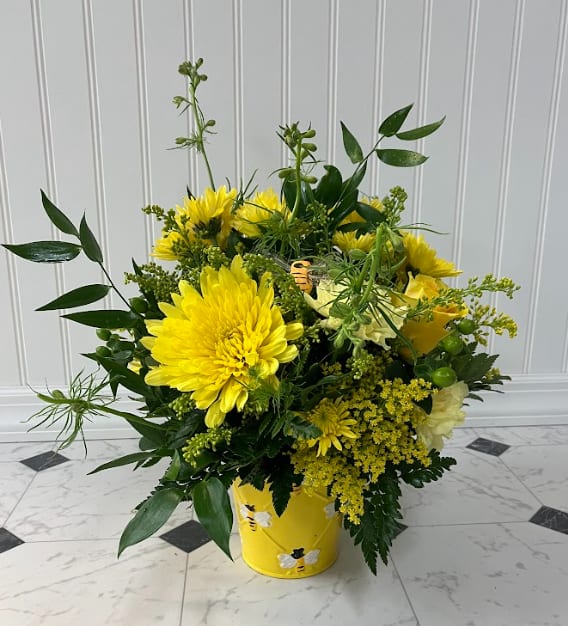 Buzzing Bee - This bright spring bumblebee floral arrangement features vibrant yellow flowers in a charming bumblebee pot. Adding to its whimsy is the adorable chubby bumblebee. Perfect for adding a touch of cheer and warmth to any room.   Matching &quot;Happy Bee-Day&quot; Balloon available for Birthday occasions!