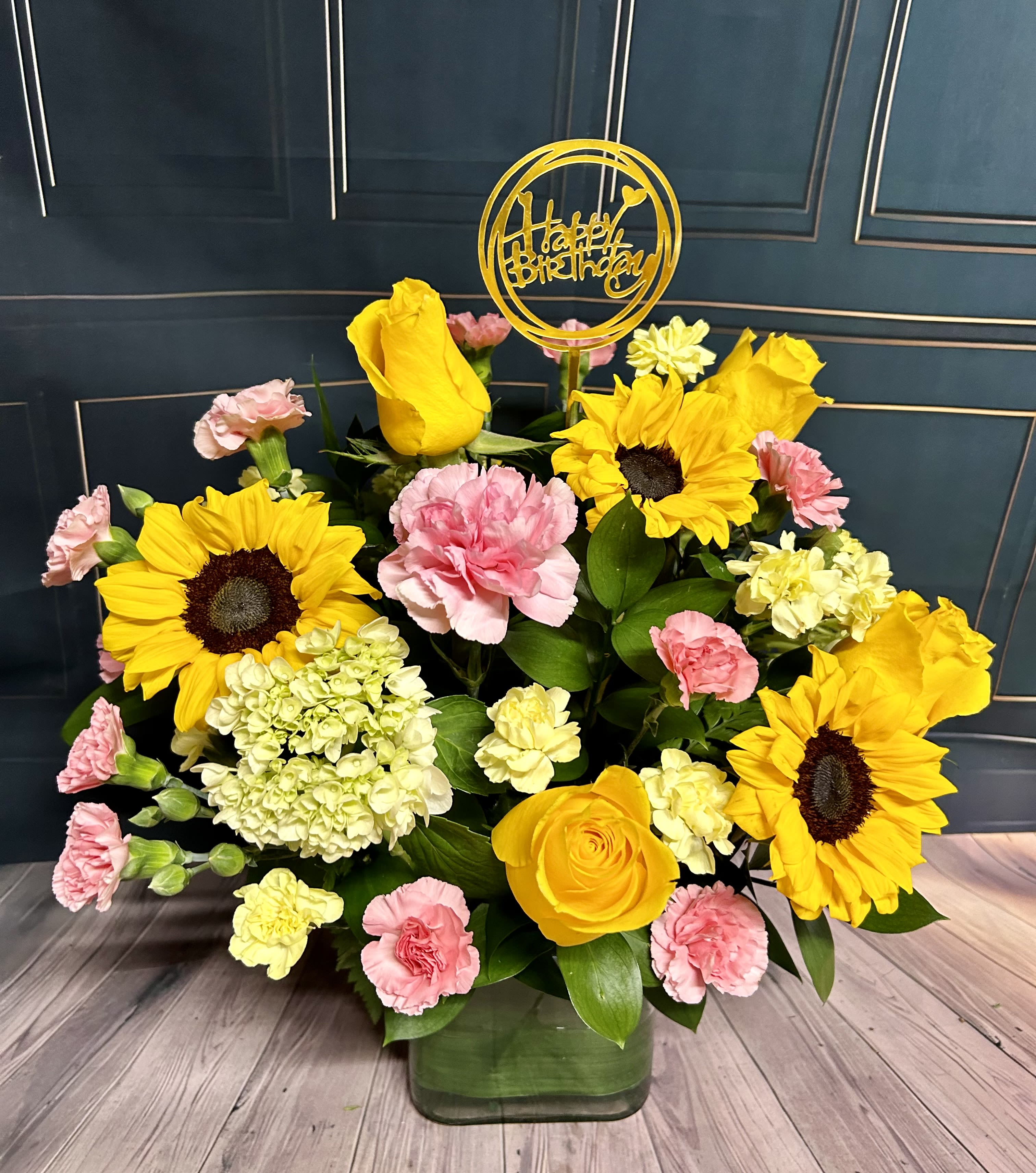 Birthday Sunflowers Birthday Sunflowers - A cubed vase arrangement of sunflowers, roses, carnations and other filler flowers made specifically for the occasion of a birthday!