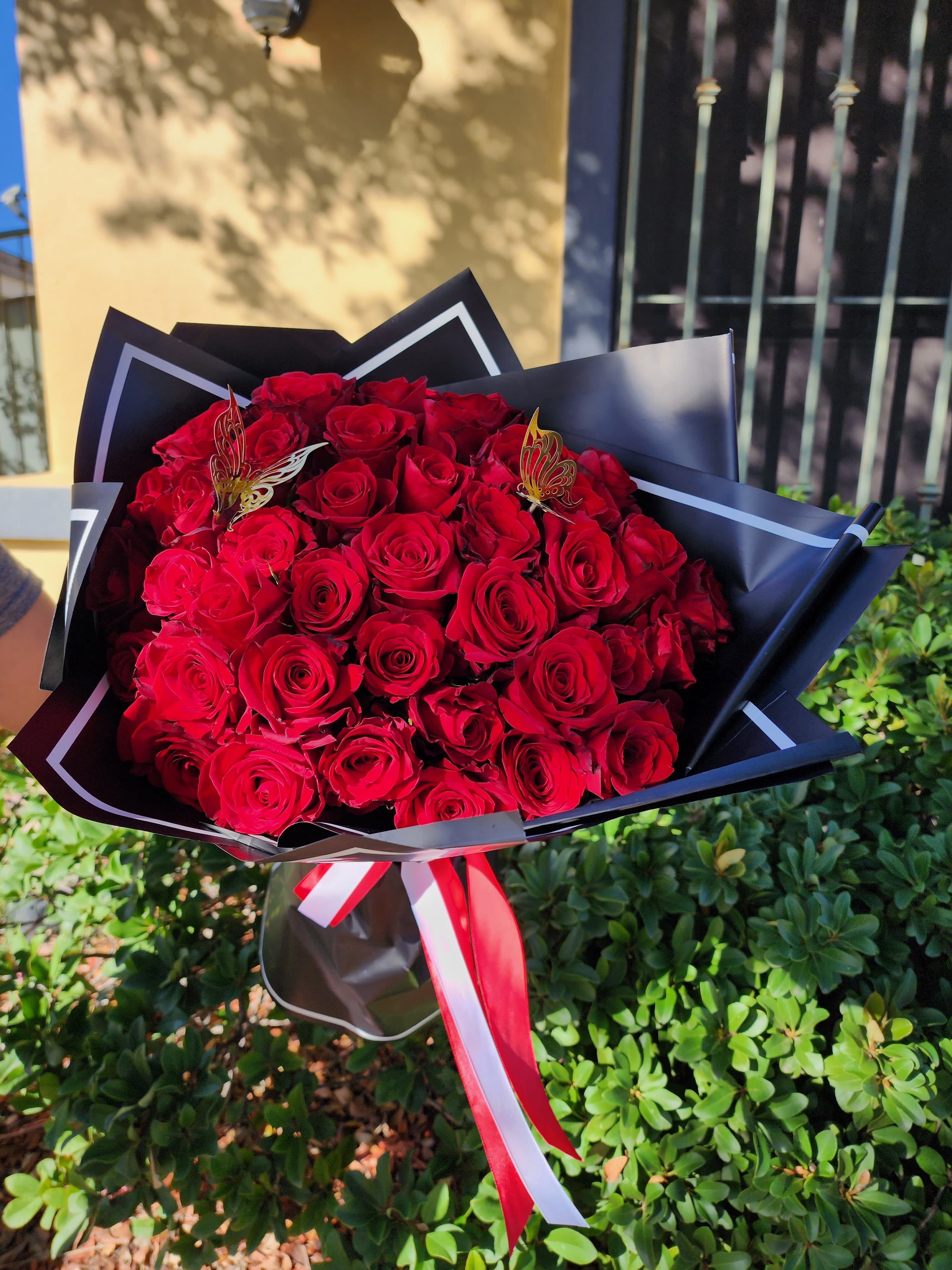 Passionate - Beautiful wrapped bouquet with 50 red roses and golden butterflies.   (Picture depicts a deluxe product; standard (50 roses) &amp; deluxe (75 roses) size available upon request)