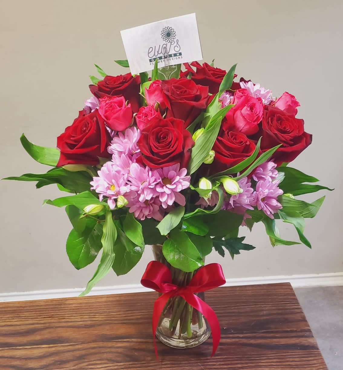 She's A Beauty - Crystal vase arrangement 12 red roses, 3 hot pink spray roses, and purple daisies.