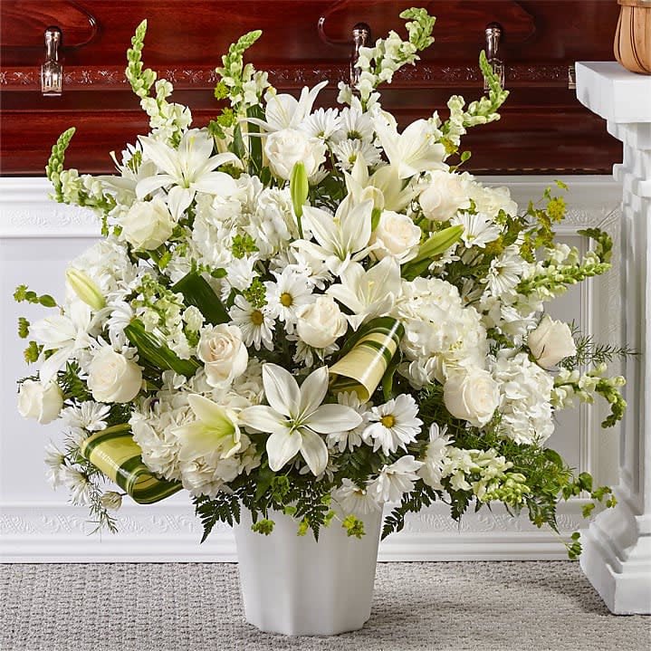 Thoughts of Tranquility Floor Basket - We present a heartfelt tribute with our all-white funeral basket, a serene arrangement filled with lilies, roses, snapdragons, hydrangeas, and more. This perfectly curated collection of flowers is designed to honor and pay respects during a somber service, bringing comfort and solace to all who encounter it.