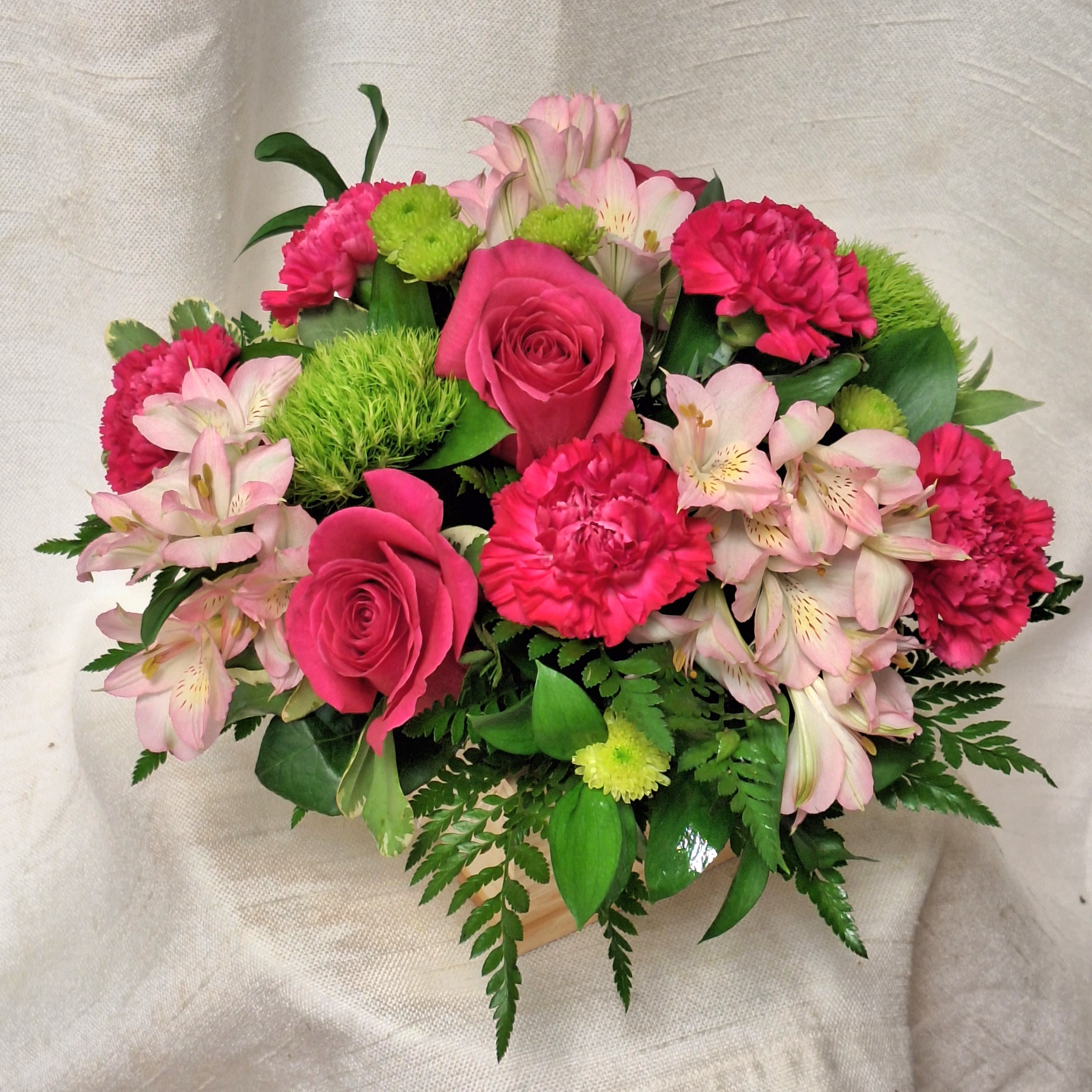Watermelon  - Indulge in the refreshing sweetness of our Watermelon Arrangement, a delightful mix of hot pink roses, pink alstroemeria, hot pink carnations, green trick, and green buttons. This vibrant ensemble is artfully arranged in a charming wooden box, creating a stunning visual contrast. Perfect for adding a pop of color to any space or as a thoughtful gift, the Watermelon Arrangement is sure to leave a lasting impression.