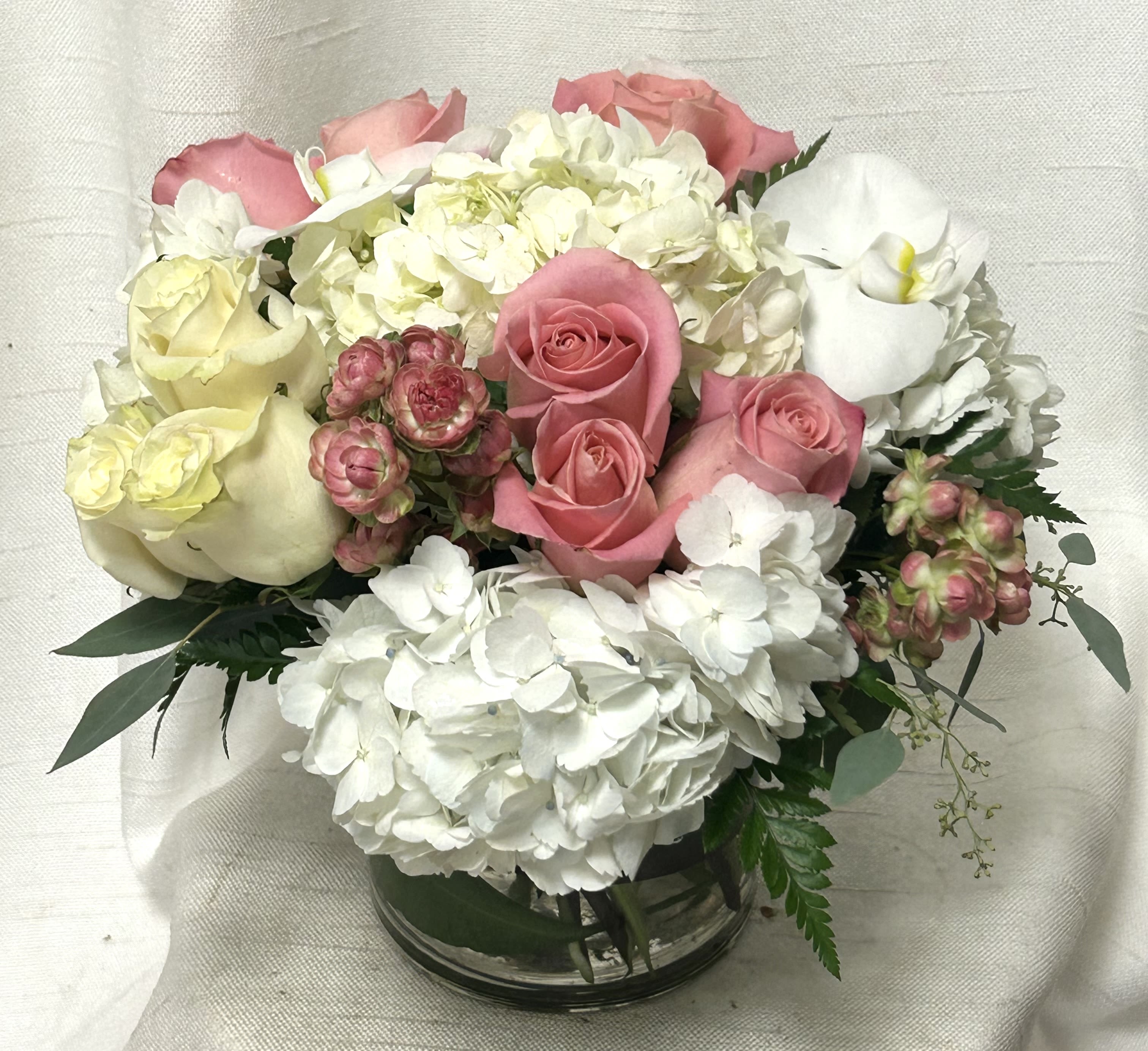 Paradise In Pink - Welcome to a floral paradise in pink with our exquisite arrangement aptly named &quot;Paradise in Pink.&quot; This stunning bouquet is a harmonious blend of delicate white hydrangea, luxurious orchids, and captivating pink roses, designed to transport you to a serene oasis of beauty and tranquility.