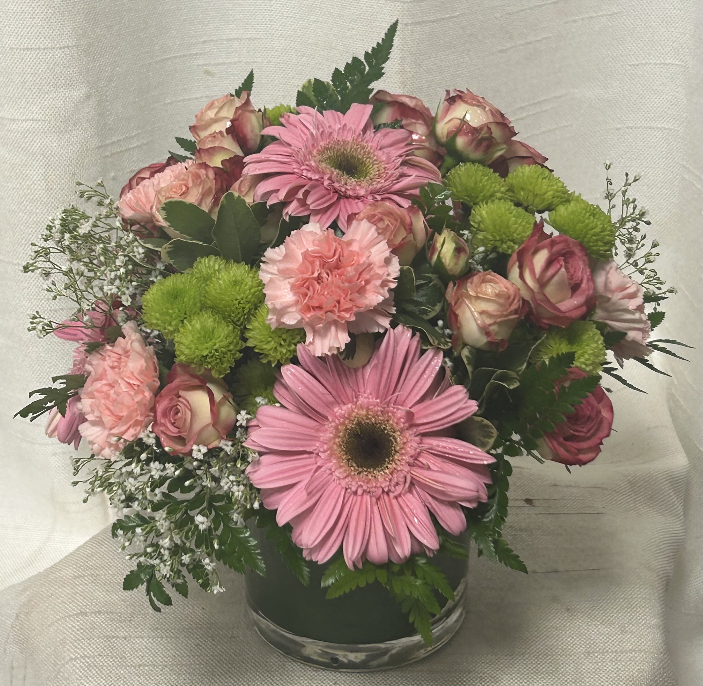 Dreamscape - Pink roses, pink mini carnations and pink gerbera daisies are accented with white Monte Casino asters and lush greens. Gorgeously arranged in a clear glass vase accented with a pink satin ribbon, this bouquet is a soft and graceful way to send your warmest sentiments.