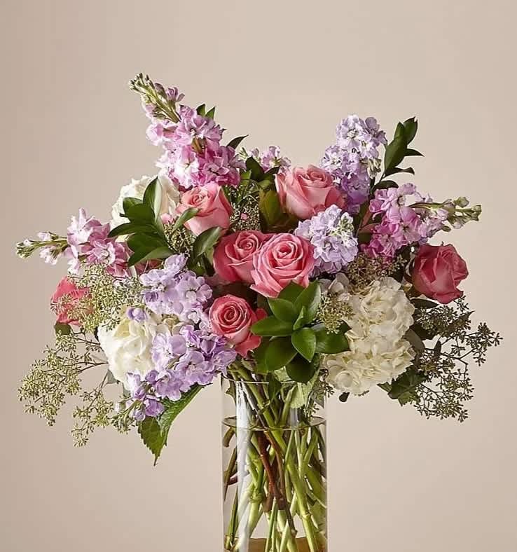 In The Garden (BB) - Experience the perfect blend of modern elegance and natural beauty with our stunning tall, In the garden floral arrangement. This meticulously designed arrangement features a captivating combination of pink roses, stock, white hydrangeas, eucalyptus, and assorted greens, all expertly arranged in a sleek 6x10&quot; leaf-lined glass cylinder vase.