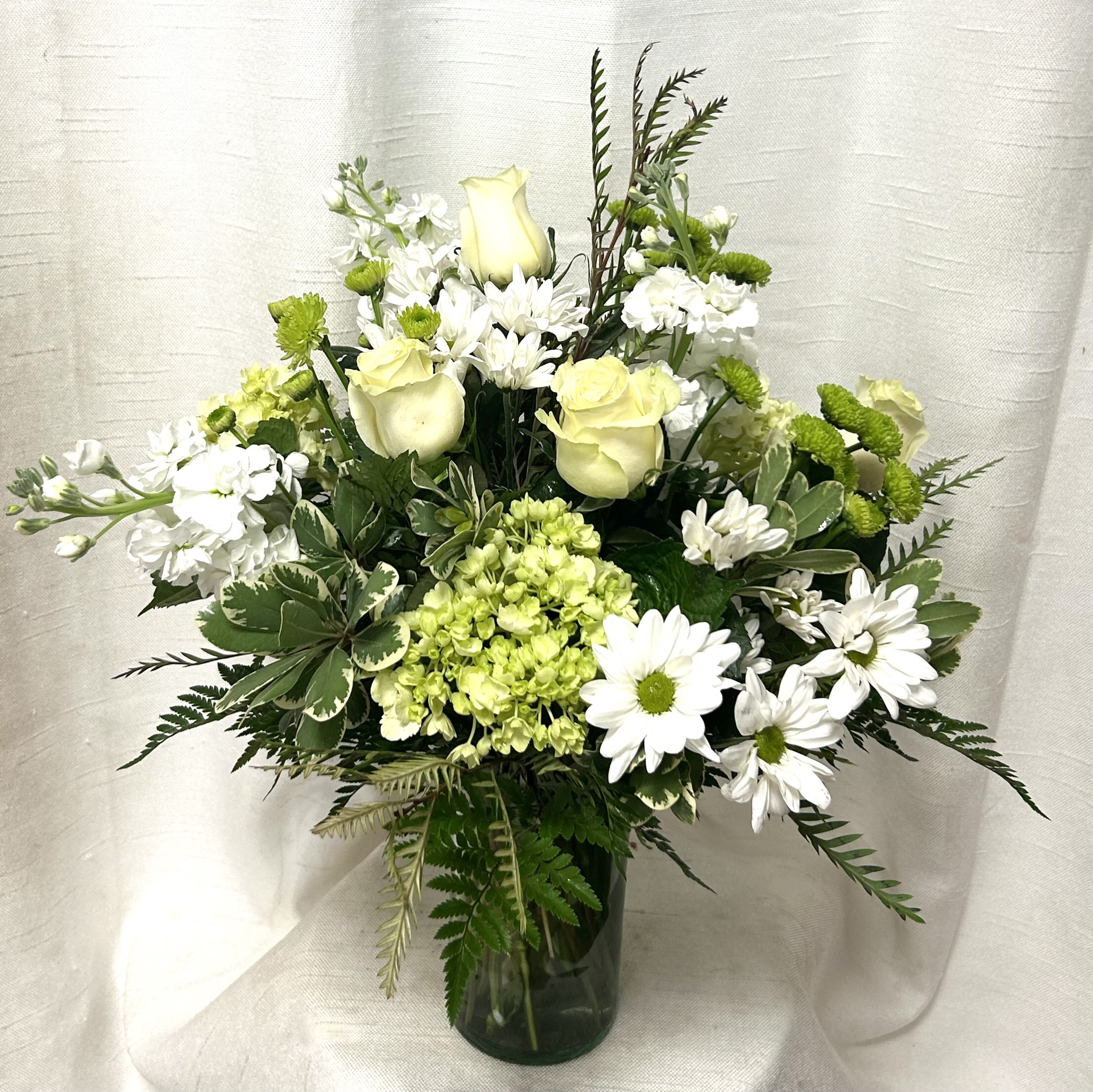 Reflective Affection (BB) - In this time of mourning, we offer a beautiful and heartfelt funeral arrangement as a tribute to your loved one. This exquisite arrangement features a delicate combination of white mini spray roses, green cushions, green hydrangea, and white pom daisies, beautifully arranged with premium greens to create a serene and elegant atmosphere.