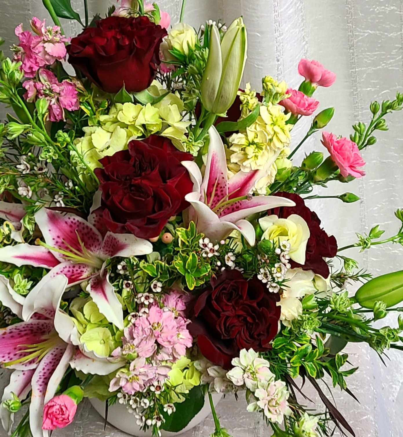 Designer's Bouquet - Mixed arrangement of premium blooms. Valentine's Day appropriate blends of deep reds, blushy cremes and bold fuschias combine with fruity scents arranged and delivered for you in a beautiful glass vase.   