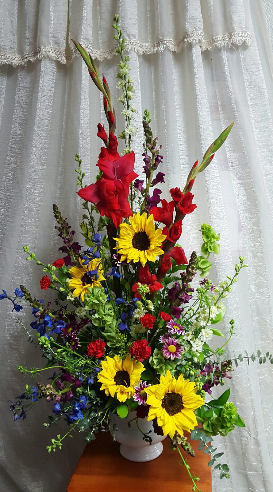 Lasting Tribute - Gladiolus, larkspur, delphinium, bells of ireland and wild sunflowers combine to create this brilliant lasting tribute.
