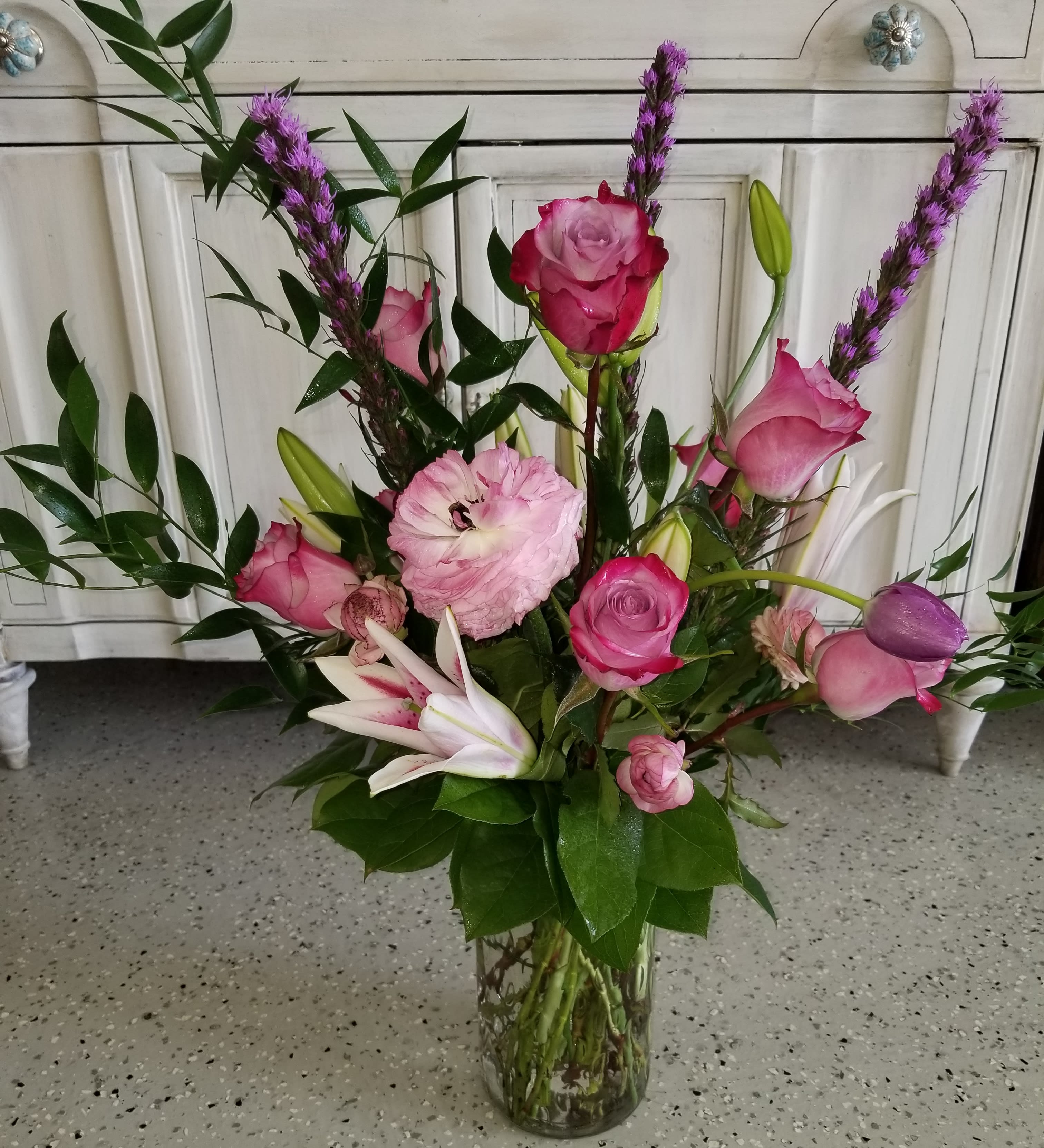 Pleasantly Purple Pleasantly Purple - This tall, show stopping arrangement designed with roses, lilies and liatris is created using different shades of purples and light pinks.