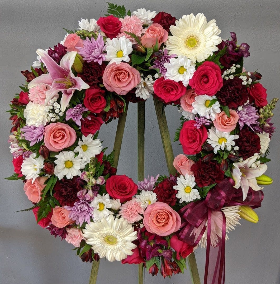 FUNERAL WREATH - Simple Elegance 63 - This is a beautiful colorful option for a funeral service, church or graveside. This open circle wreath will be designed with an 18”, 24&quot;, or 30&quot; circle form and will be delivered on a stand. This lovely mix of white, pink and purple flowers of roses, lilies, daisies and carnations is a perfect option to honor the colorful life you are celebrating.    **This is a piece for a funeral or memorial service. Please place the order at least 2 days prior to the service to guarantee a certain arrangement. Anything sooner and we cannot guarantee it will match the picture. These pieces can be customized to the color of your choice. The flowers may vary depending on availability of the flowers, special requests and quality of the flowers we have in stock. If you have a special request please add it to our special instructions when placing your order. If you have any questions please don’t hesitate to call. 714 289 1123**