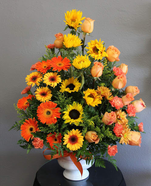 FUNERAL FLOOR SPRAY - Sunshine on a Rainy Day 85 - This is floor spray is a great way to add some sunshine to a memorial or funeral service. This arrangement is an “A” shaped one sided flower arrangement that stands approximately 3.5' tall and 2.5' wide for the standard and will be slightly larger and fuller if upgraded. This lovely mix of yellow and orange sunflowers, roses and Gerber daisies is a wonderful way to remember the bright moments in one's life.  **This is a piece for a funeral or memorial service. Please place the order at least 2 days prior to the service to guarantee a certain arrangement. Anything sooner and we cannot guarantee it will match the picture. These pieces can be customized to the color of your choice. The flowers may vary depending on availability of the flowers, special requests and quality of the flowers we have in stock. If you have a special request please add it to our special instructions when placing your order. If you have any questions please don’t hesitate to call. 714 289 1123**