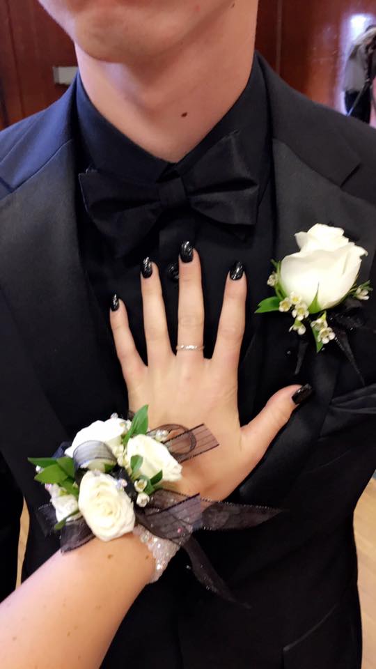 White & Black Wrist Corsage and Boutonniere to Matc White & Black Wrist Corsage and Boutonniere to Matc - Our signature custom made wrist corsage with white spray roses and accented with black ribbon and wax flower or babies breath set on an iridescent slap wristlet with custom made rose boutonniere to match. Also contains add-on iridescent rhinestones. We have a wide range of ribbon options and rose colors to choose from. Feel free to visit us at our shop to pick out a custom corsage and boutonniere for you. NO SAME DAY ORDERS