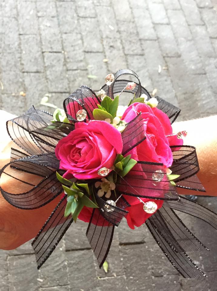 Hot Pink &amp; Black Wrist Corsage  - Our signature custom made wrist corsage with hot pink spray roses and accented with black ribbon and wax flower set on an iridescent beaded wristlet. Also contains add-on iridescent rhinestones.  We have a wide range of ribbon options and rose colors to choose from. Feel free to visit us at our shop to pick out a custom corsage for you.