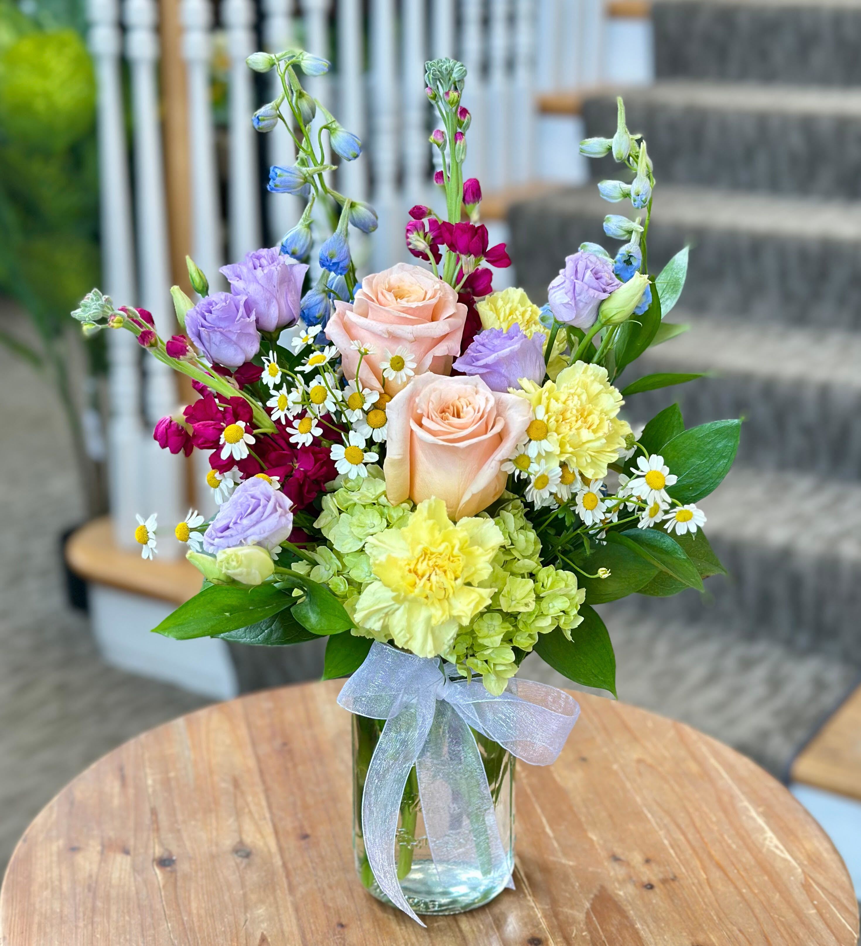 Freshly Picked Bouquet - SPRING &amp; SUMMER COLLECTION | LOCAL DELIVERY ONLY  A sweet and simple bouquet with a &quot;just-picked&quot; feel. Designed in a clear mason jar, this garden-inspired arrangement features a charming mix of green hydrangea, roses, stock, delphinium, lisianthus, carnations, and feverfew. Dainty, cheerful &amp; full of wildflower charm - it's like bringing a bit of the meadow indoors.