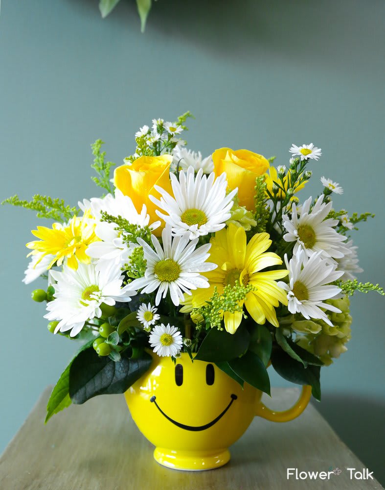 Be Happy Be Happy - Yellow roses, white and yellow daises are arranged in a yellow happy face mug. Perfect to cheer up or brighten anyone's day!