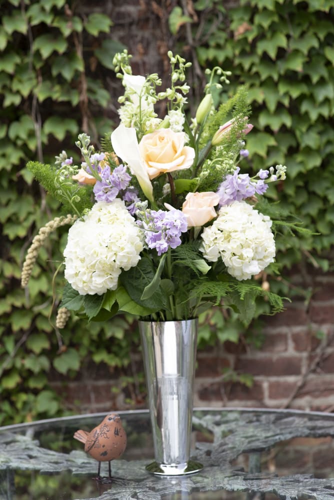 Sleek and Light Sleek and Light - A sleek silver trumpet vase fully stocked with white hydrangea, purple stock, calla lilies, roses, and pink lilies.