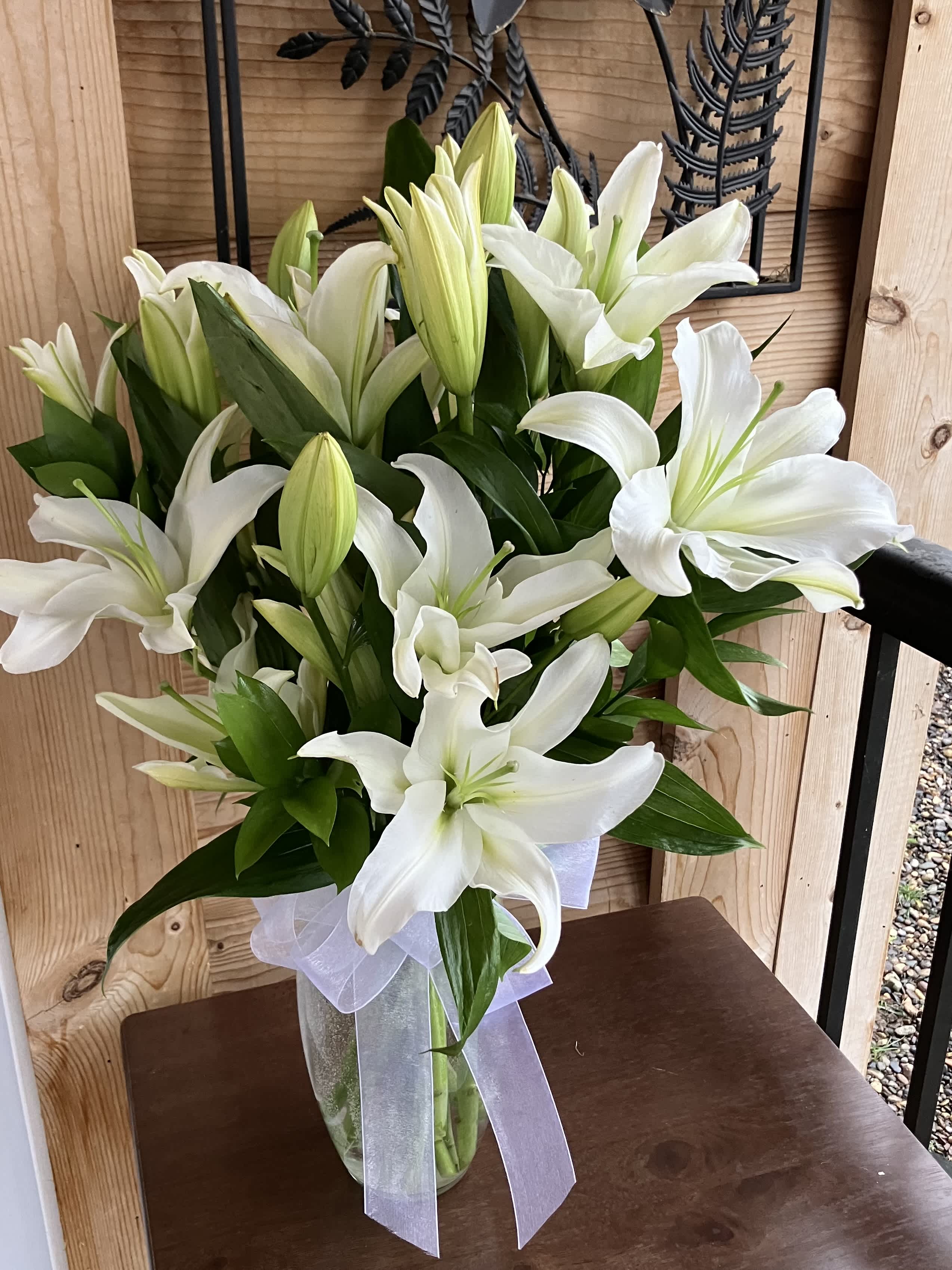 White Sympathy Bouquet - White lilies stand tall and beautiful. Send an impactful gift to somebody whether it be for saying I am sorry or celebrating the new year. This arrangement instantly elevates any room and fills the space with that distinct sweet-smelling lily perfume.  1st Image: Standard 2nd Image: Premium