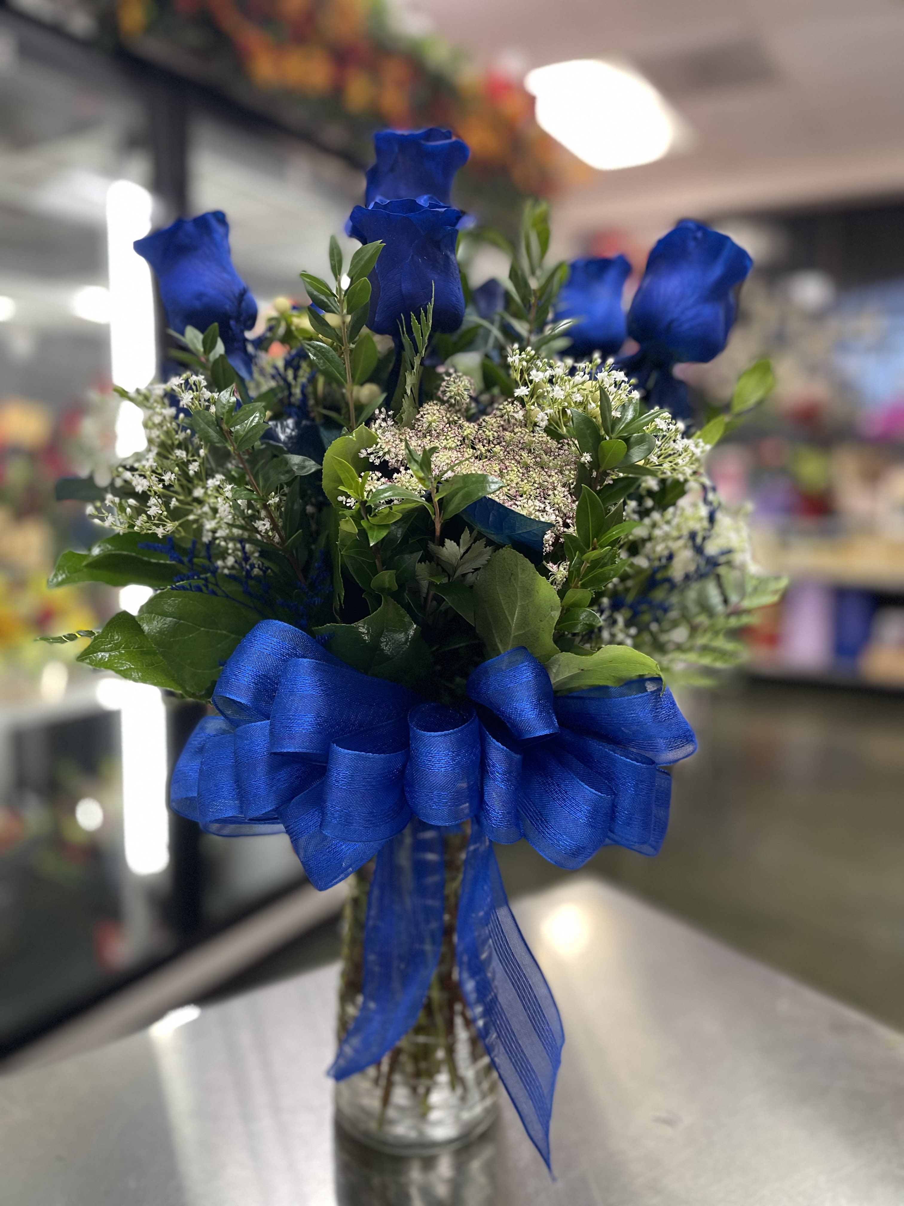 Processed Blue Rose - Glass Vase Processed Blue Rose - Glass Vase - WE NEED 7 DAY NOTICE TO ORDER THESE ROSES. These roses are what we considered “processed blue roses”. The roses DRINK a special blue water making it look very natural and real.