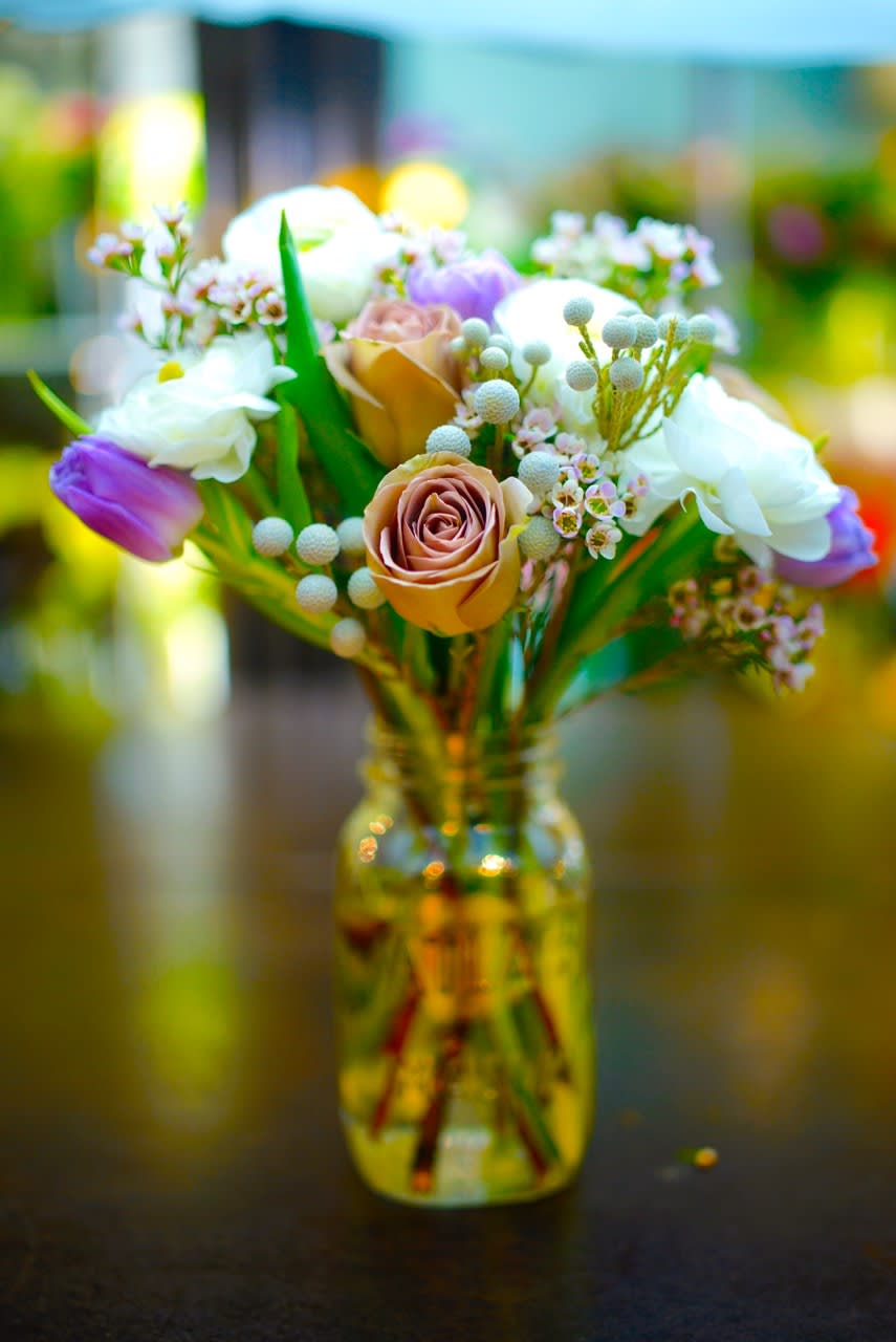 PEACHES AND CREAM PEACHES AND CREAM - A simple yet delightful arrangement of soft peach Amnesia roses, fluffy white ranunculus, silver brunia, and purple tulips. Delicate pink gillyflowers complete this sweetly soft design.