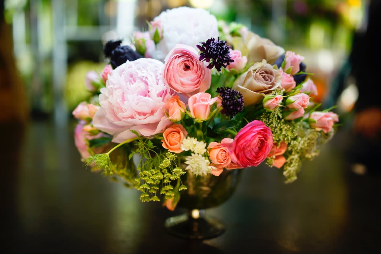 PINK GARDENS PINK GARDENS - Fluffy pink peonies, soft pink ranunculus, wild Queen Anne's Lace, rich burgundy scabiosa, and deep purple artichokes are a delight in this luxurious and extravagant design. Displayed in a mercury glass vase.