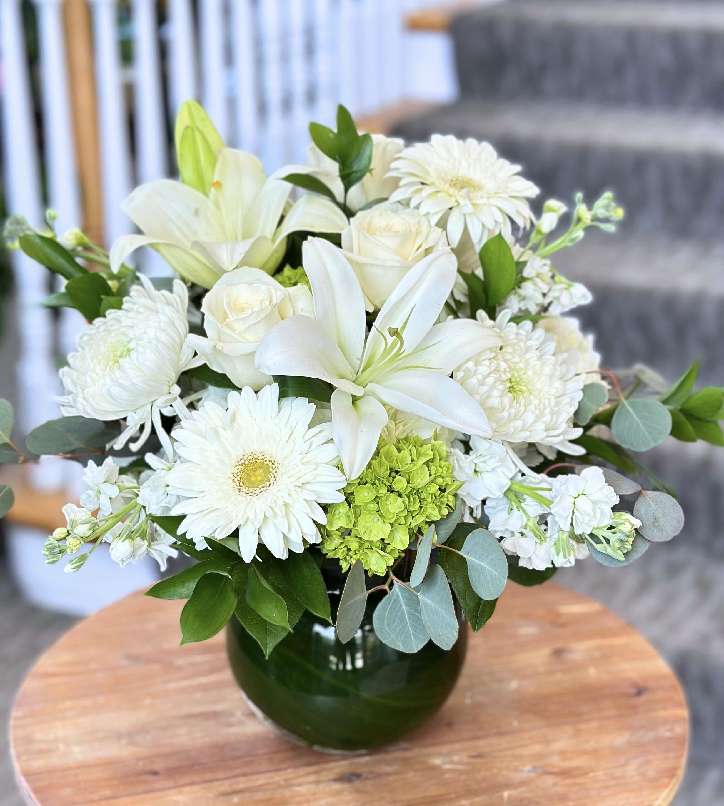 Ivory Elegance Bouquet - EVERYDAY COLLECTION | LOCAL DELIVERY ONLY  A serene statement of beauty, the &quot;Ivory Elegance Bouquet&quot; features a lush, all-white blend of lillies, roses, hydrangea, gerbera daisies, and stock. Designed to be full and abundant in soft texture and timeless charm, this arrangement brings a sense of peace, and sophistication to any space. Perfect for moments of celebration, remebrance or simply to surround someone with a tasteful arrangement. 