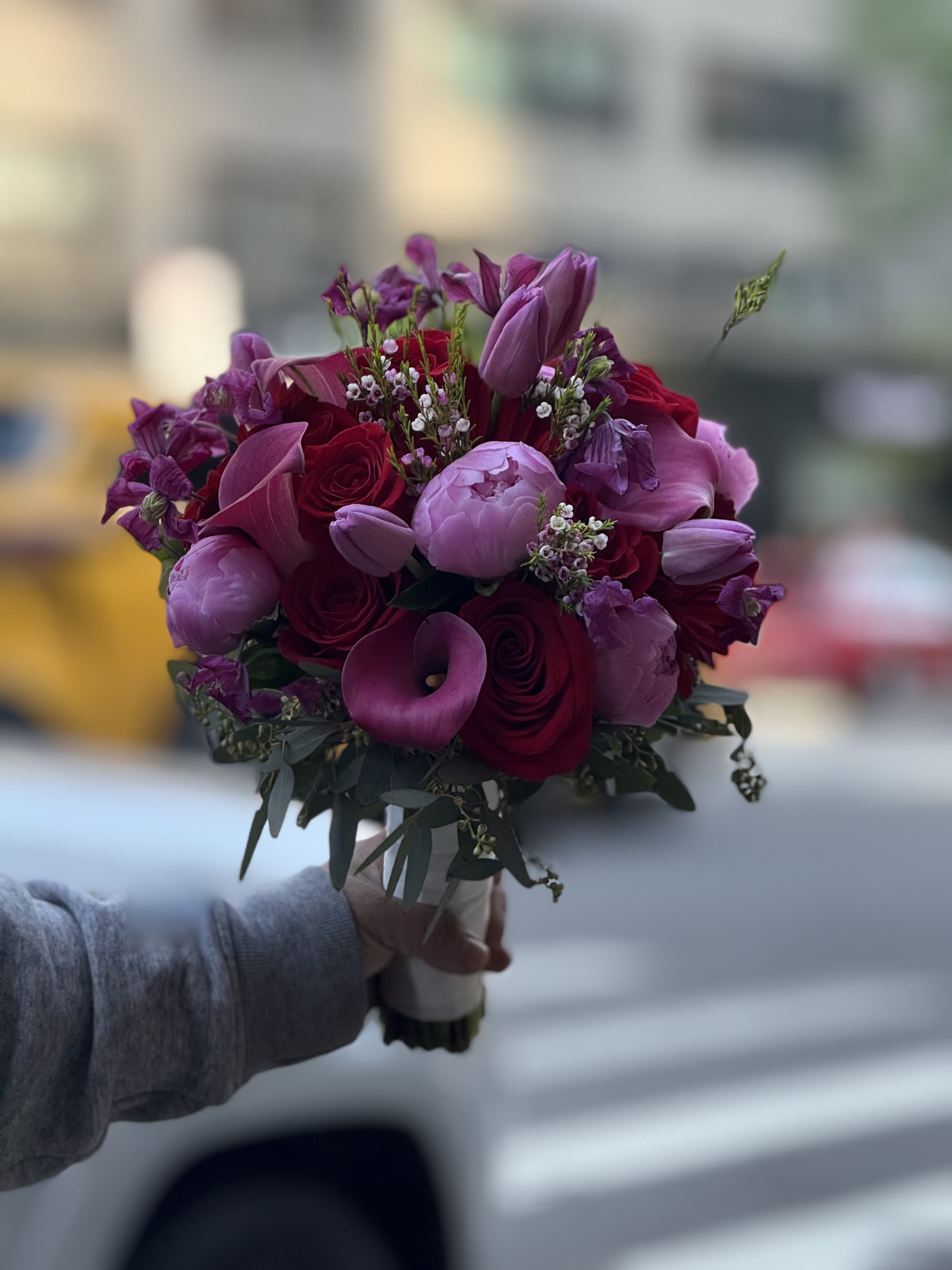 Velvet Amour - This elegant and romantic hand-tied bouquet is a rich composition of deep reds and soft pinks, perfect for a luxurious, passionate statement. The stems are neatly wrapped in a satin white ribbon adorned with pearls, giving it a polished, bridal-ready finish.
