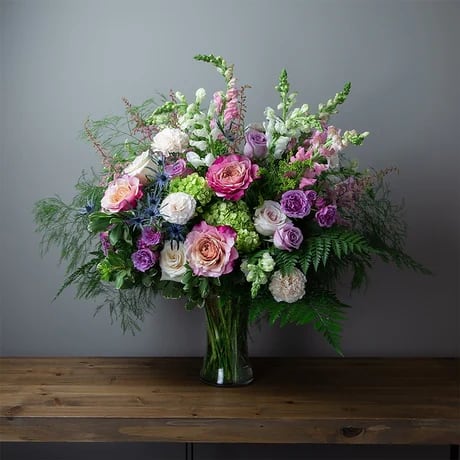 Donna's Gardeners Glory - Sure to delight anyone, this thoughtful vase arrangement of pink, green, white, peach, lavender, blue and yellow featuring flowers like, hydrangea, snapdragons, carnations, roses, r, spray roses, eryngium and solidago with seasonal Florida foliage like pittosporum, leather leaf and tree fern.  DGTMF-1353