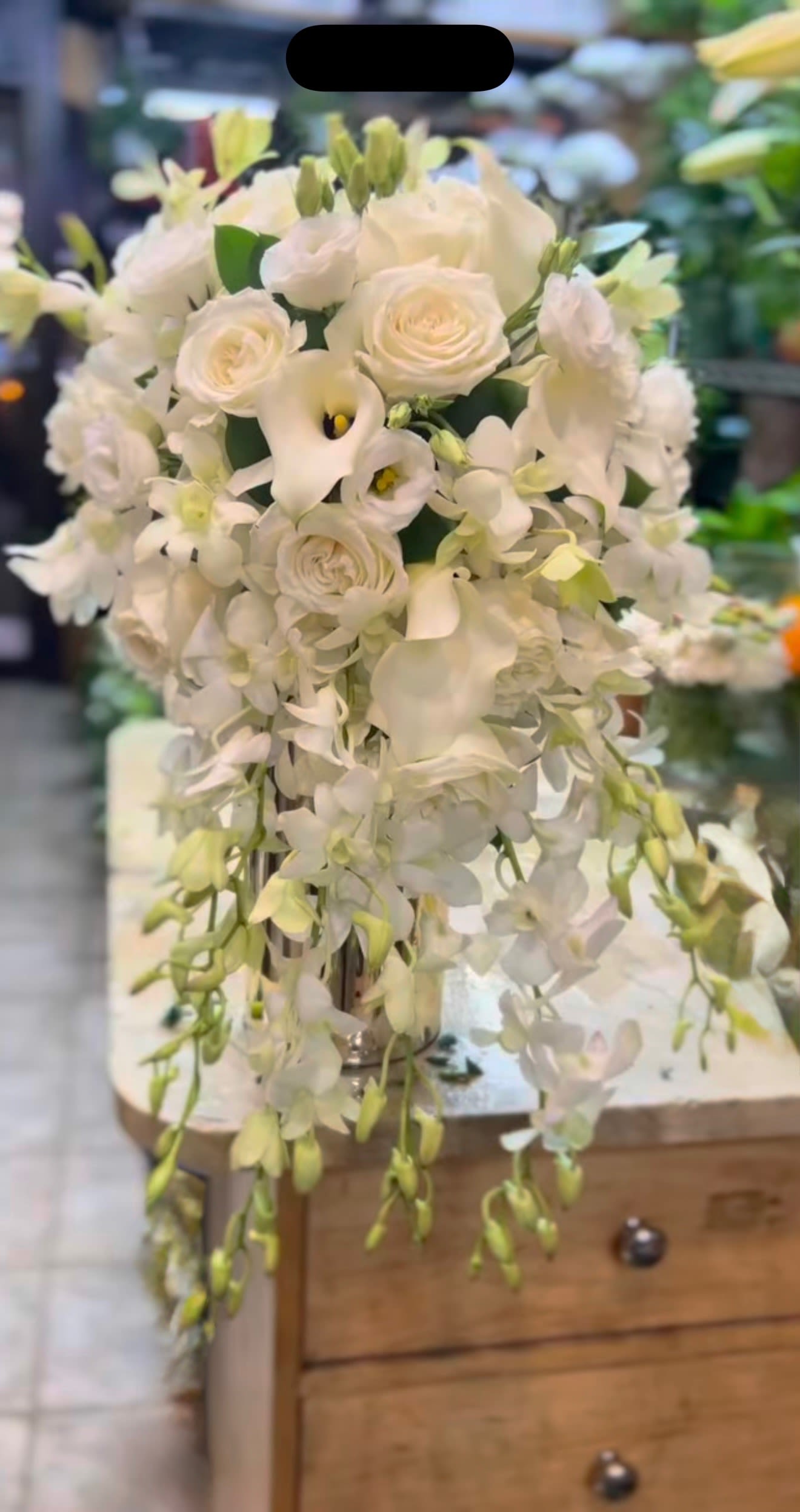 Ivory Grace  - A vision of pure elegance, this all-white bridal bouquet captures the essence of classic romance. Featuring a graceful blend of premium white roses, delicate orchids, and airy lisianthus, each bloom is carefully selected for its soft texture and natural beauty. Accented with seasonal foliage, the bouquet is artfully hand-tied with silk ribbon for a refined, effortless look. Perfect for the modern bride who cherishes understated luxury and timeless charm.