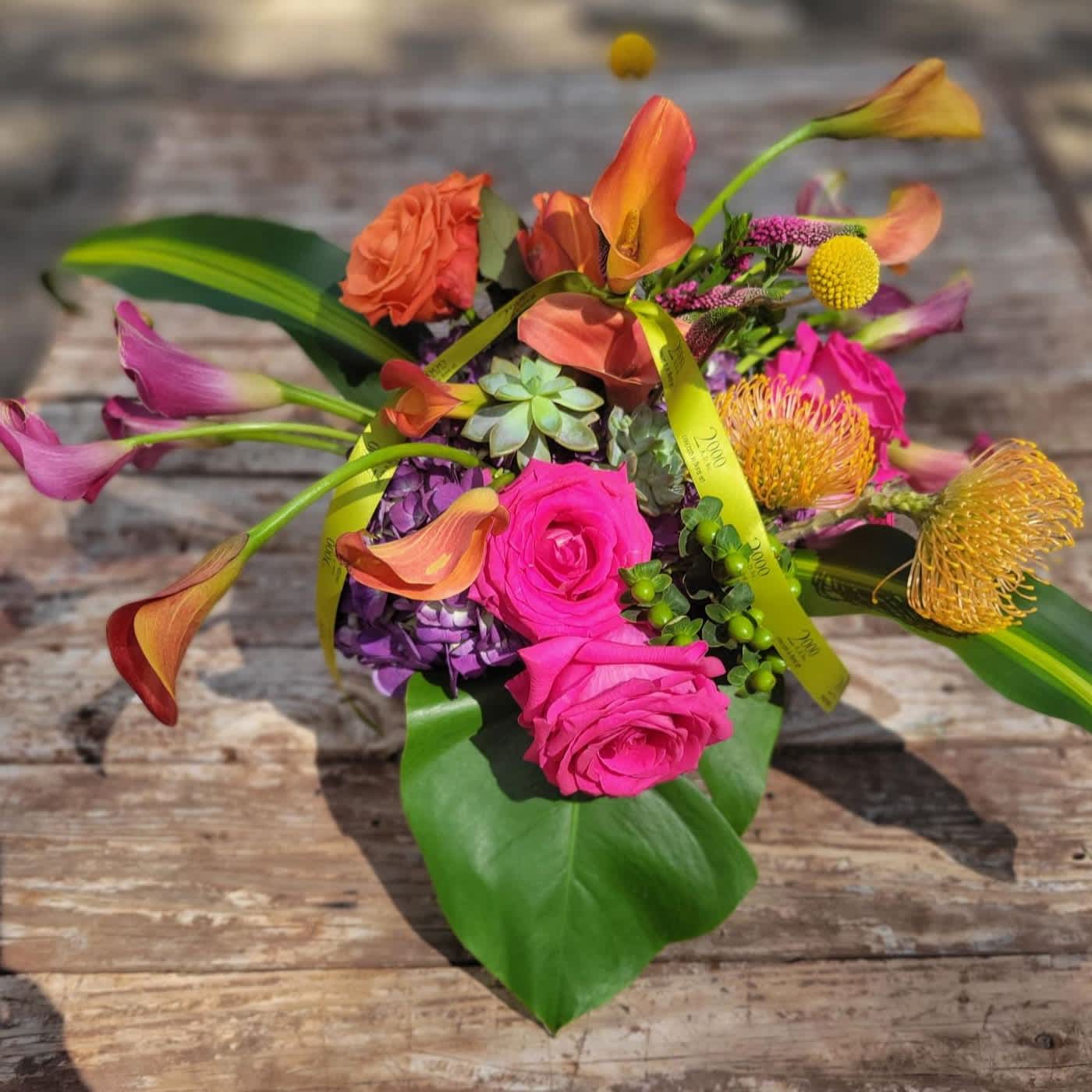 Barbados Barbados - Festive and colorful mixture of seasonal blossoms. Executed in clear glass container with exposed stems.