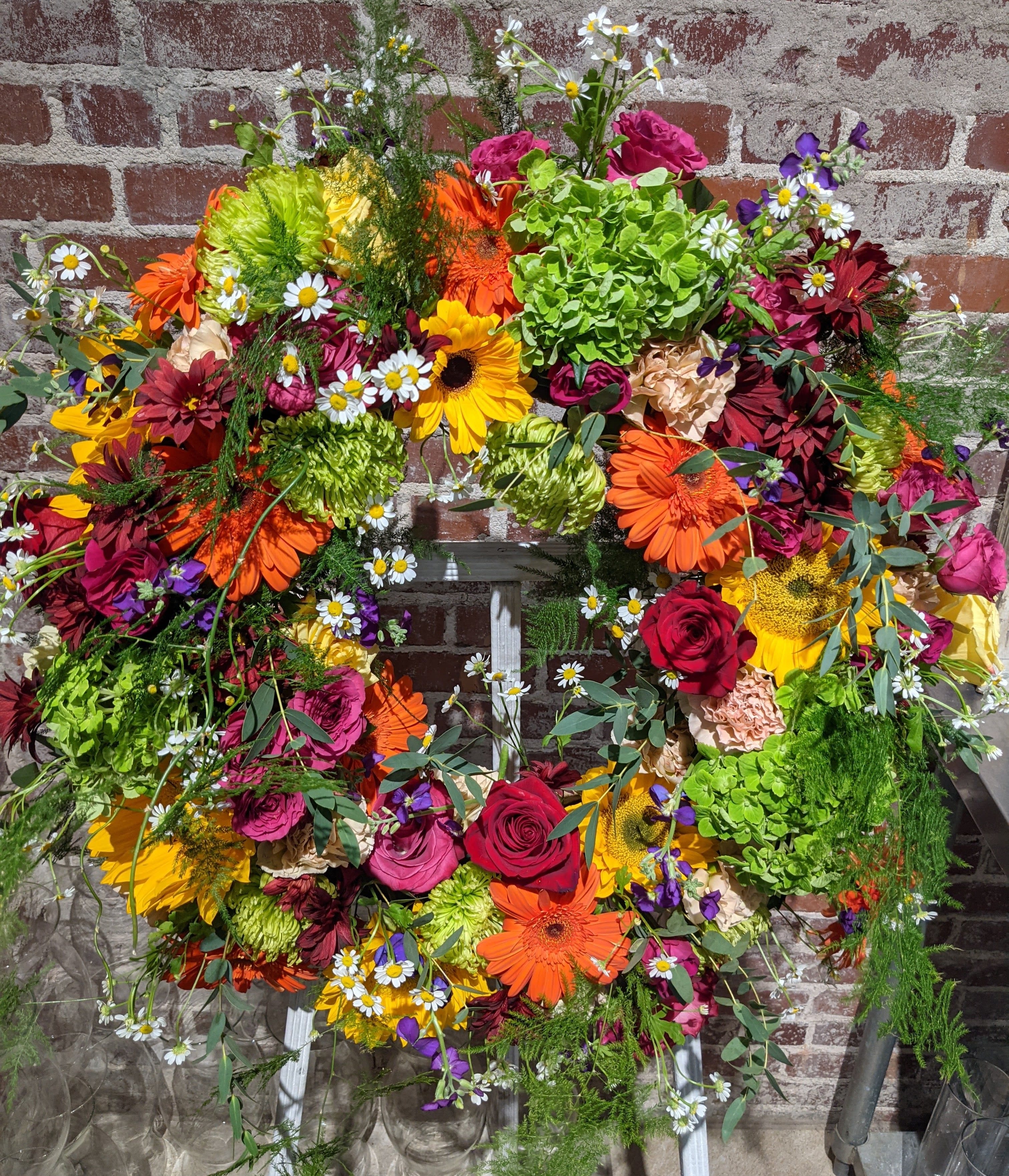 Garden Memorial Wreath Garden Memorial Wreath - Classic large memorial wreath designed with multi-colored flowers and accented with ferns and foliages. Ribbon and bow accent available upon request.